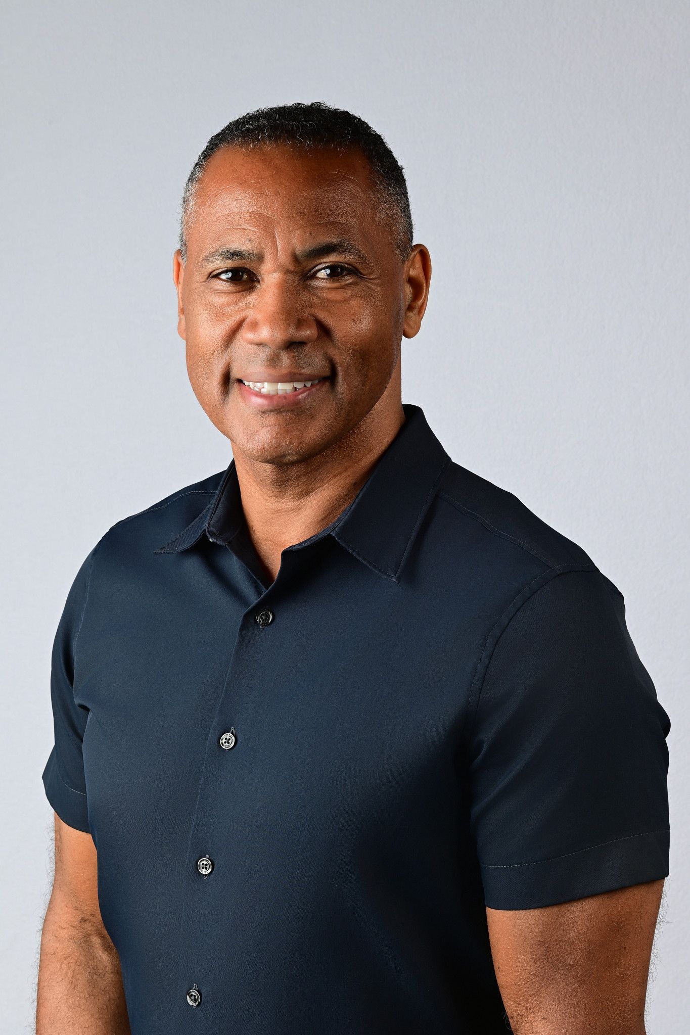 Smiling middle-aged Black man in navy blue button-up shirt poses for professional headshot photo.