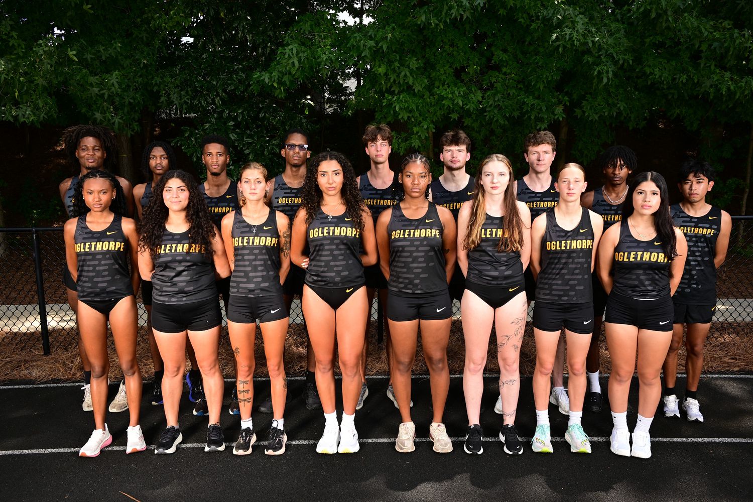 Haltom High School track and field team poses together in black uniforms on an outdoor track.