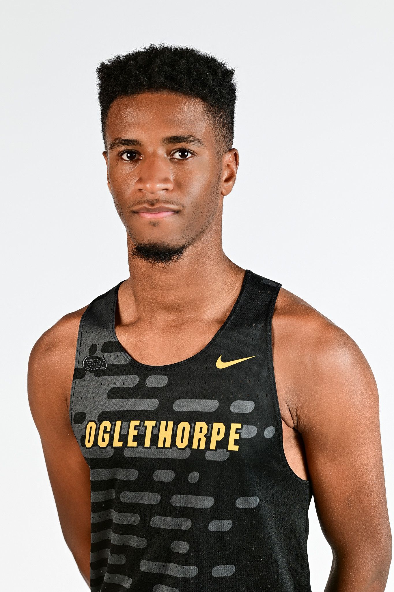 Oglethorpe University male track athlete in black Nike uniform posing seriously against white background.