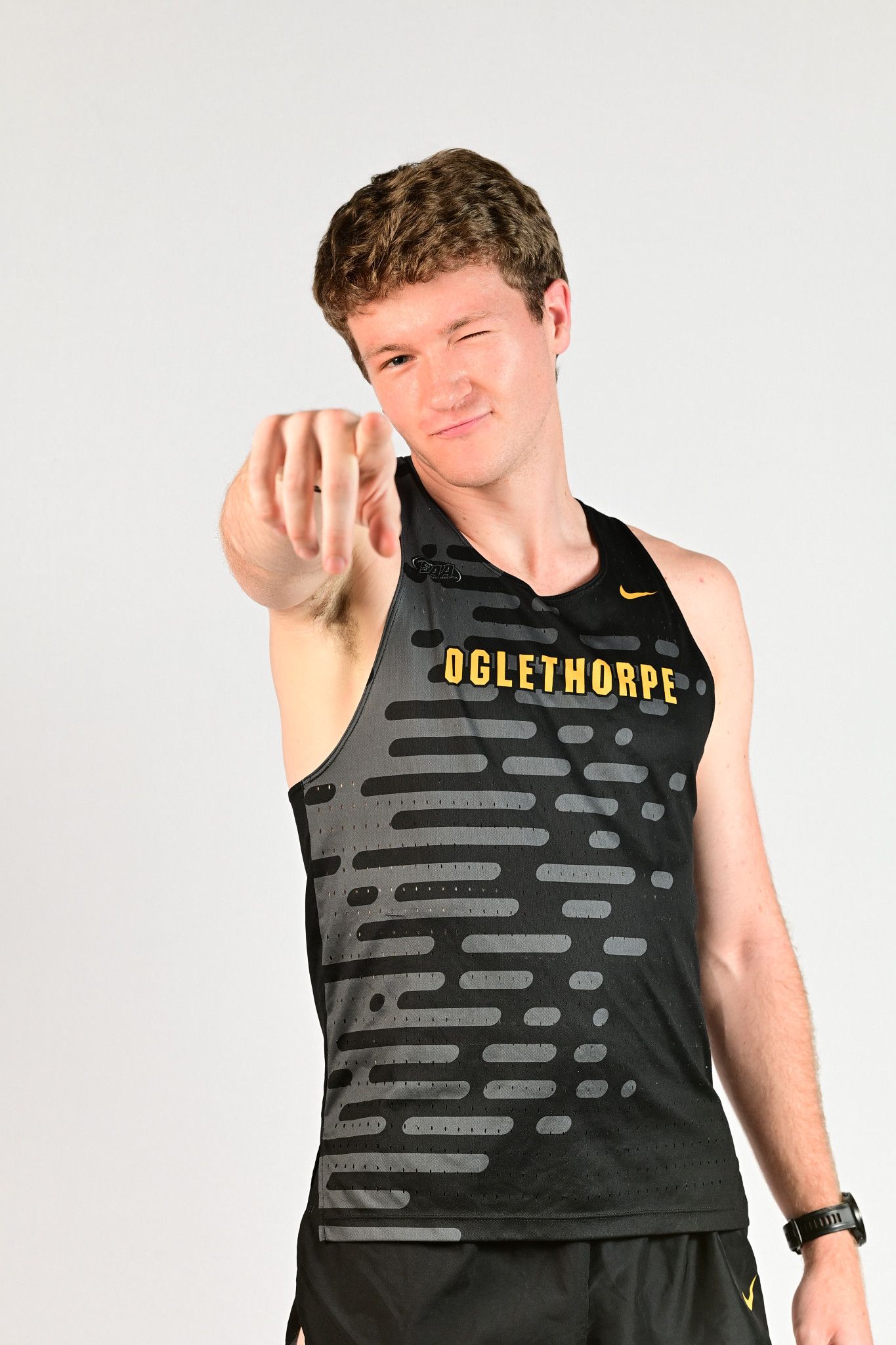 Oglethorpe University athlete in black Nike track jersey pointing forward during sports portrait photo shoot.