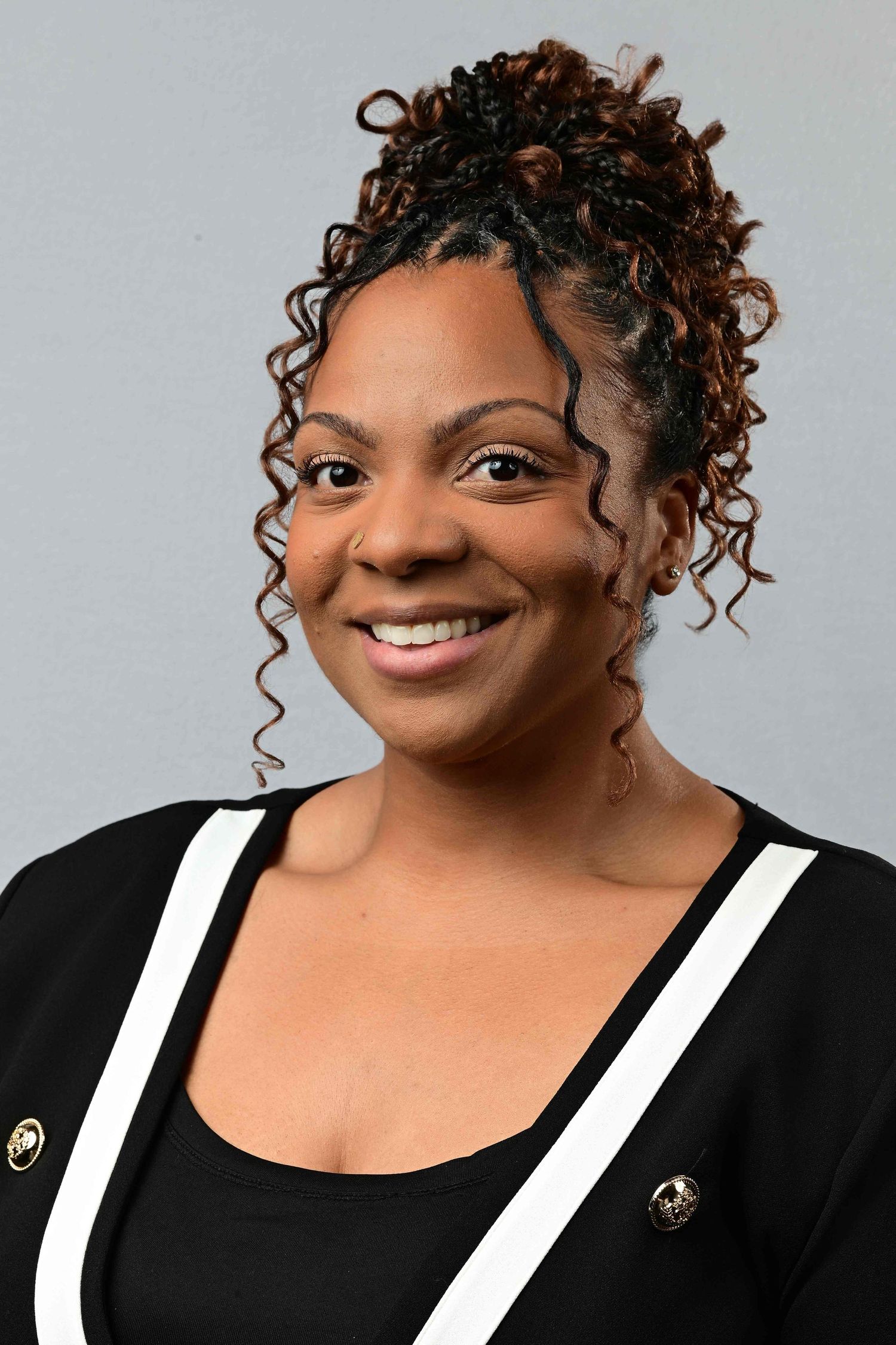 Professional headshot of a smiling woman with curly updo hair wearing a black and white outfit.