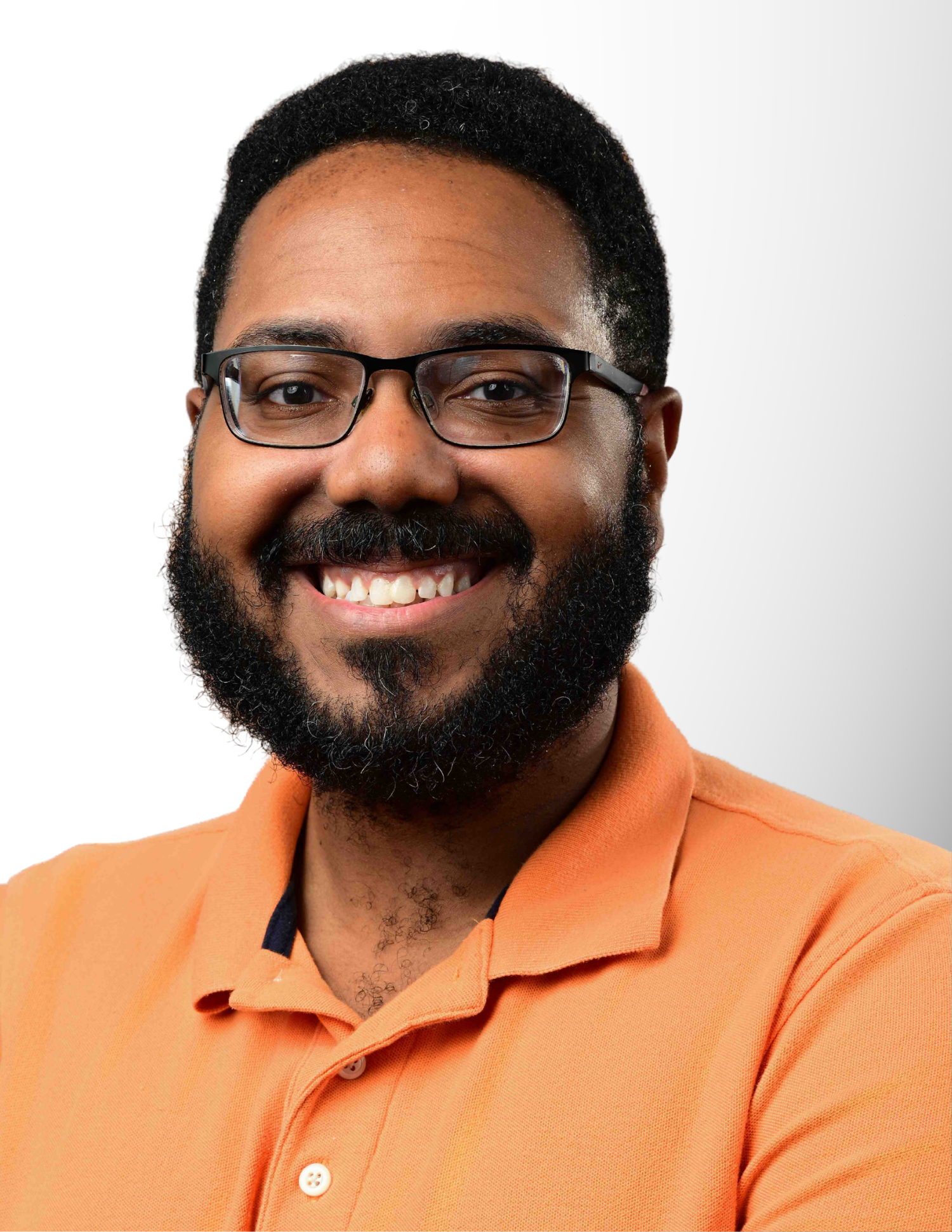 Smiling man with beard and glasses wearing an orange polo shirt against a light gray background.