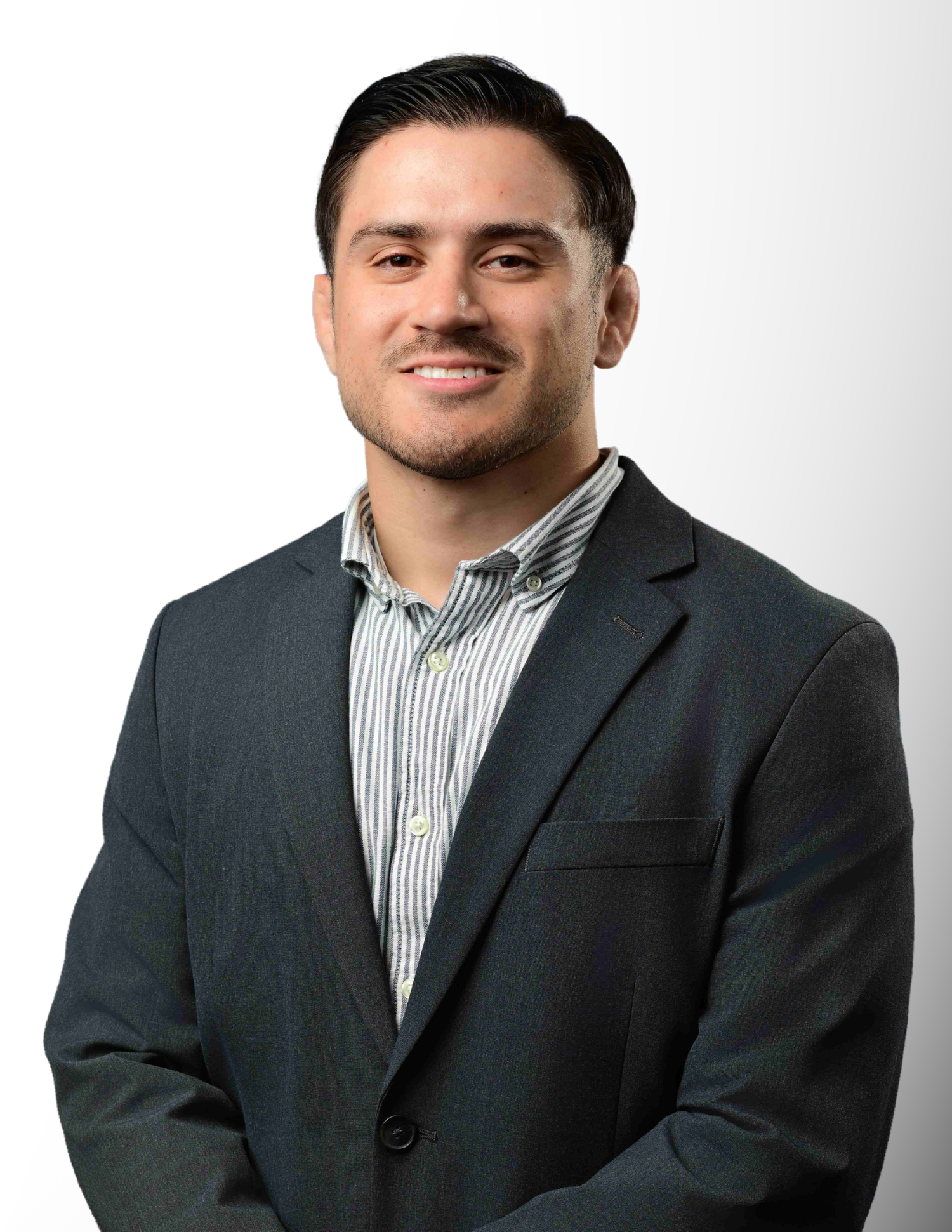 Professional headshot of a smiling young man in a dark blazer and striped shirt against a white background.