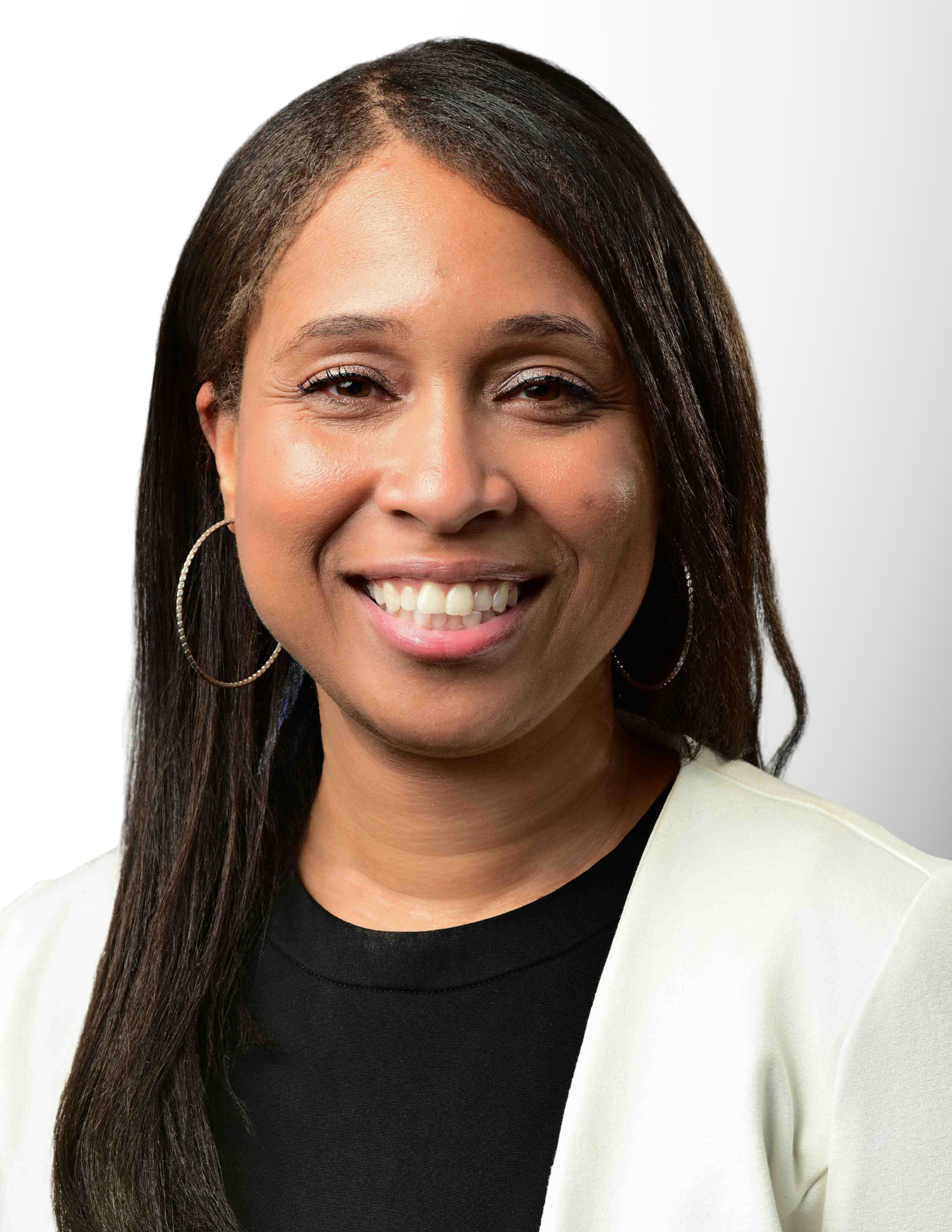 Professional headshot of a smiling woman wearing a white blazer and gold hoop earrings against a light background.