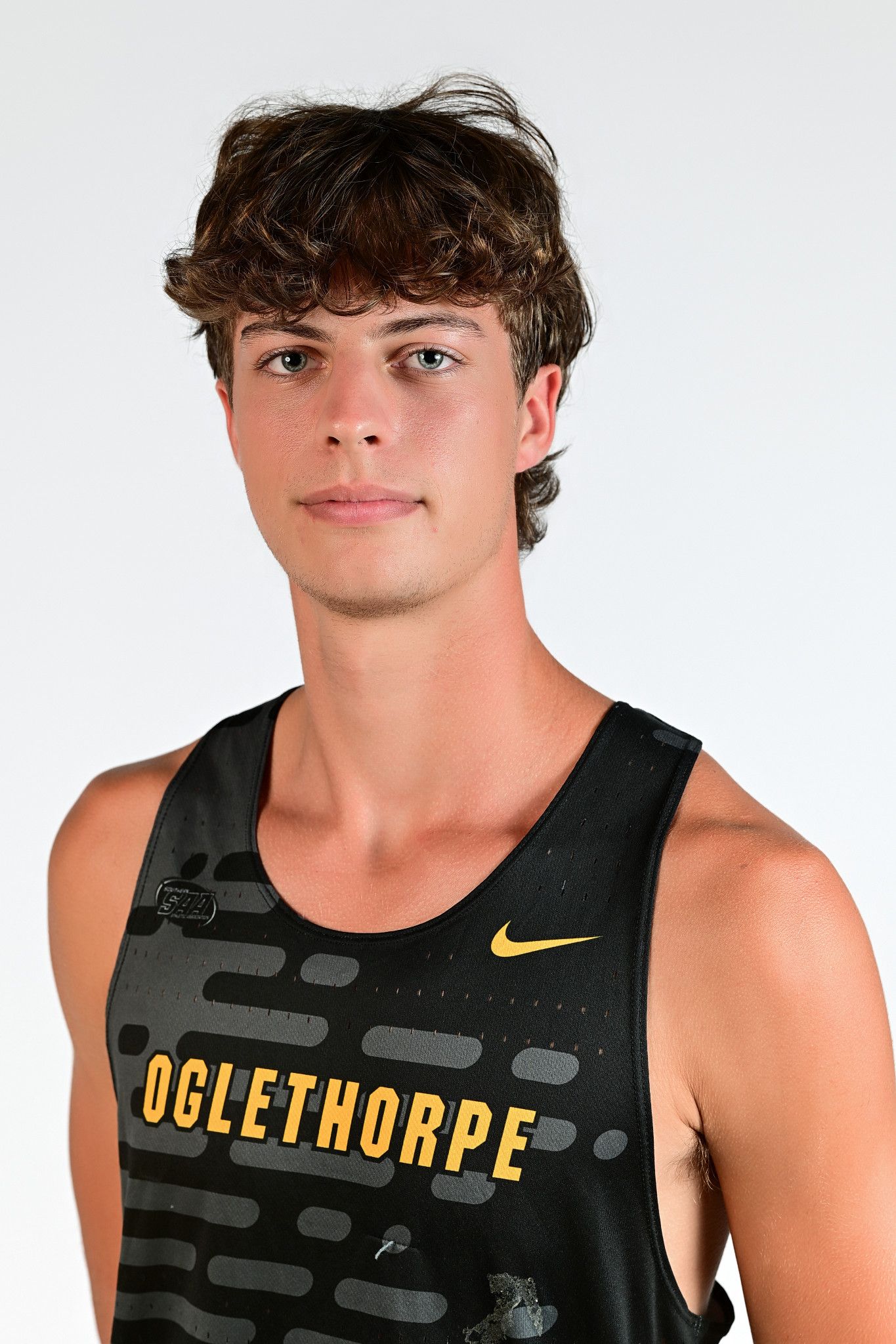 Oglethorpe University male track athlete poses in black and gold Nike uniform for official sports portrait.