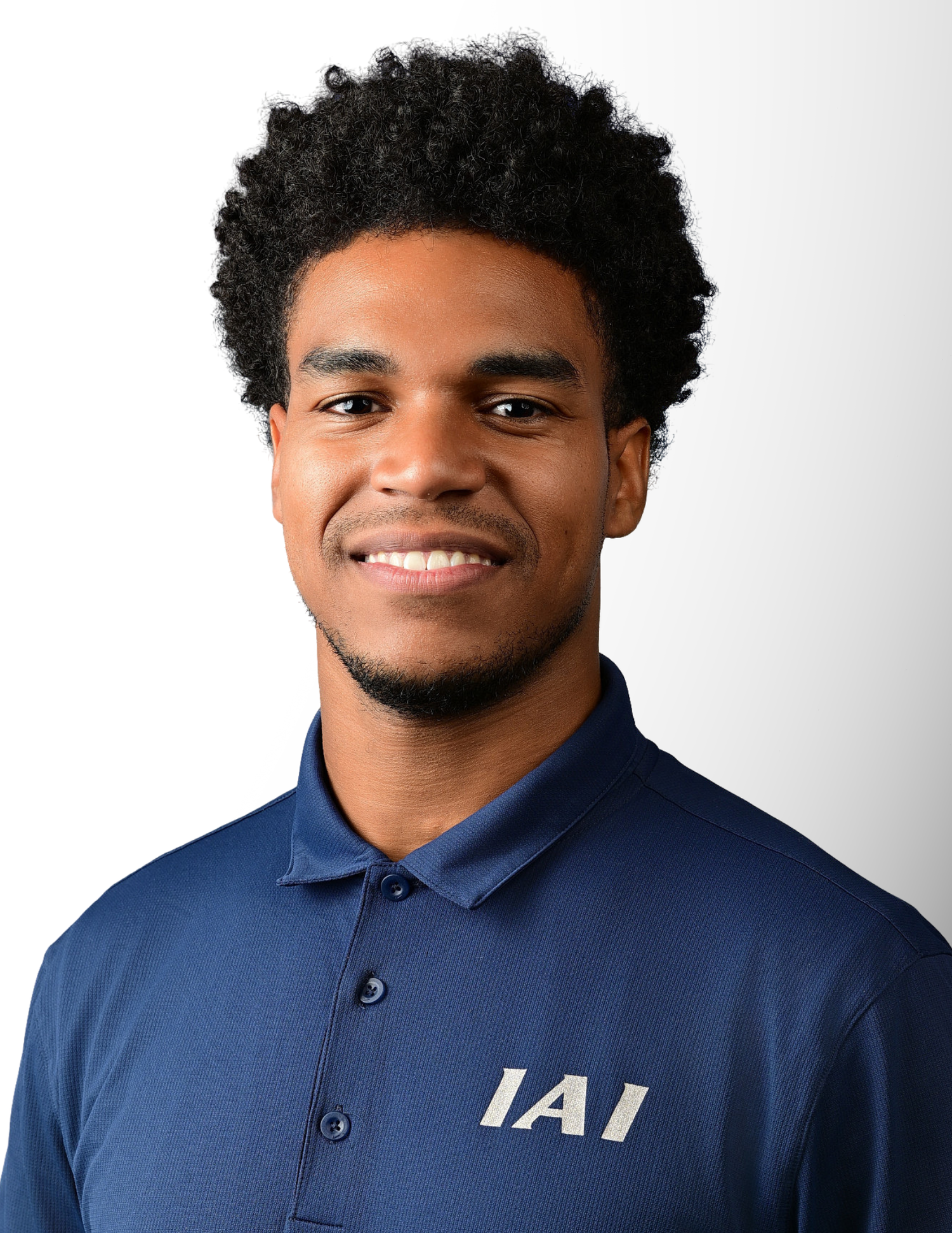 Young man smiling in a navy blue IAI polo shirt against a white background.