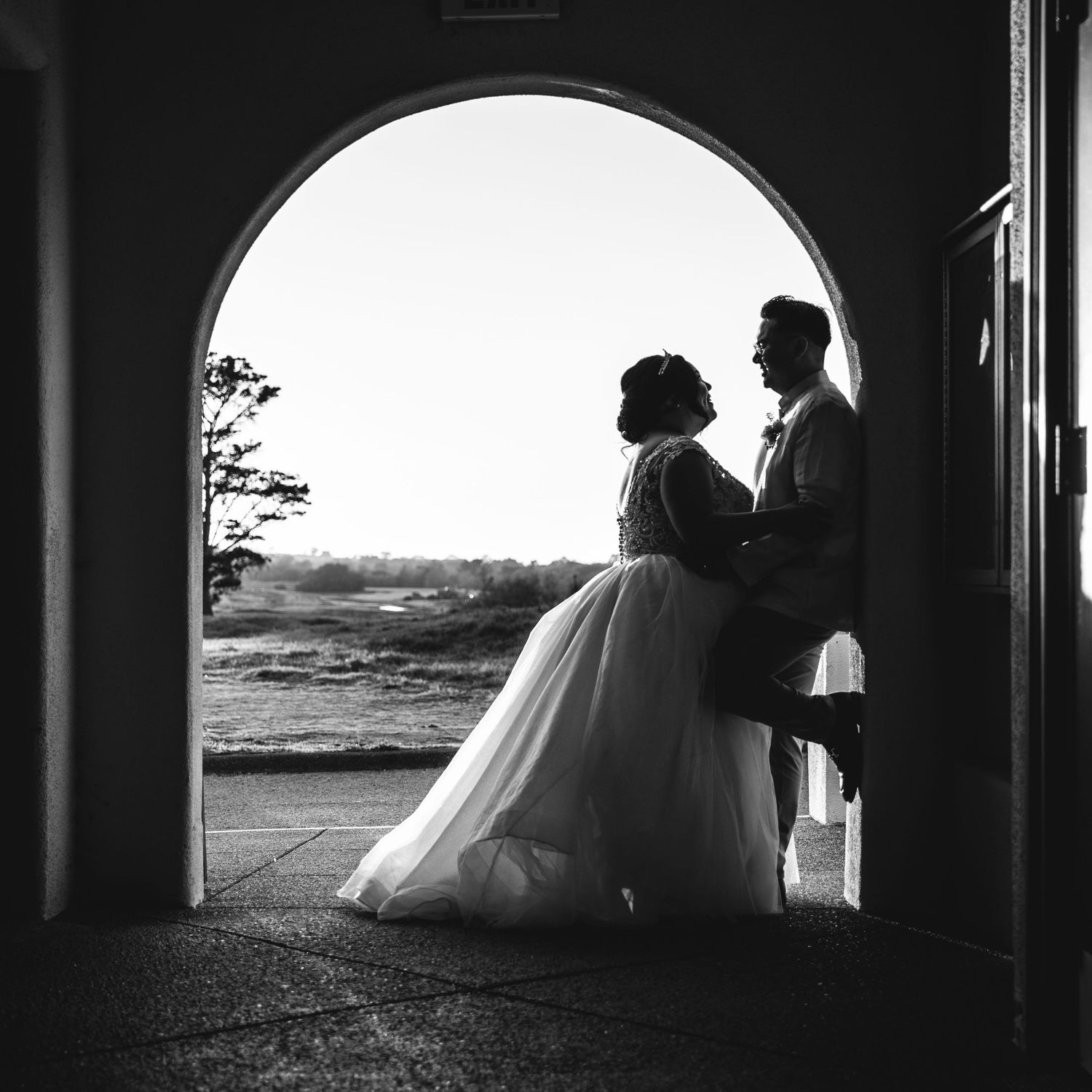 Black and white silhouette of a bride and groom standing in an arched doorway with scenic outdoor backdrop in San Jose Wedding.