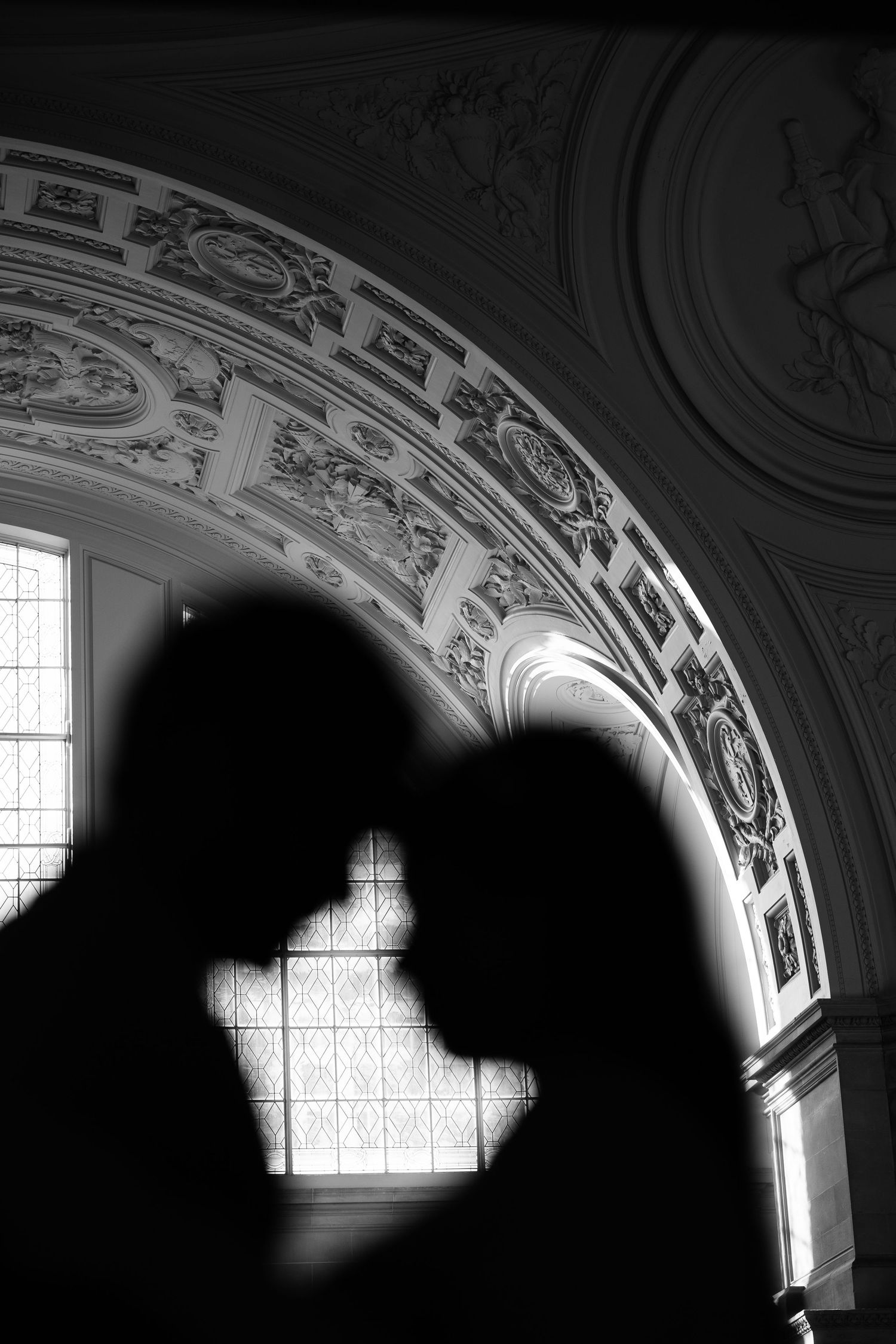 Black and white photo of a couple sharing a romantic moment at a San Francisco City Hall Wedding with ornate architecture.