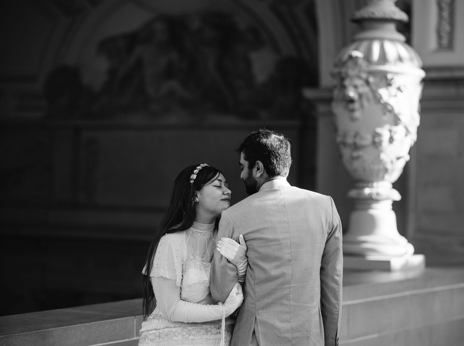 Black and white photo of a couple sharing a romantic moment at a San Francisco City Hall Wedding with ornate architecture.