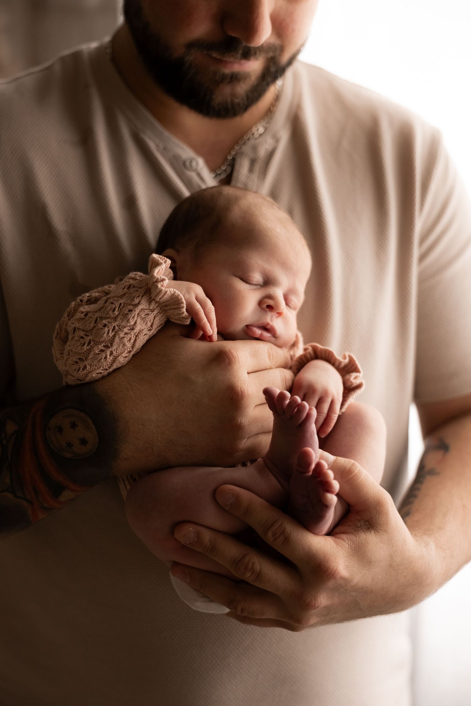 A new dad hold his newborn baby in lovely soft lighting in the Perth hills glen Forrest newborn studio