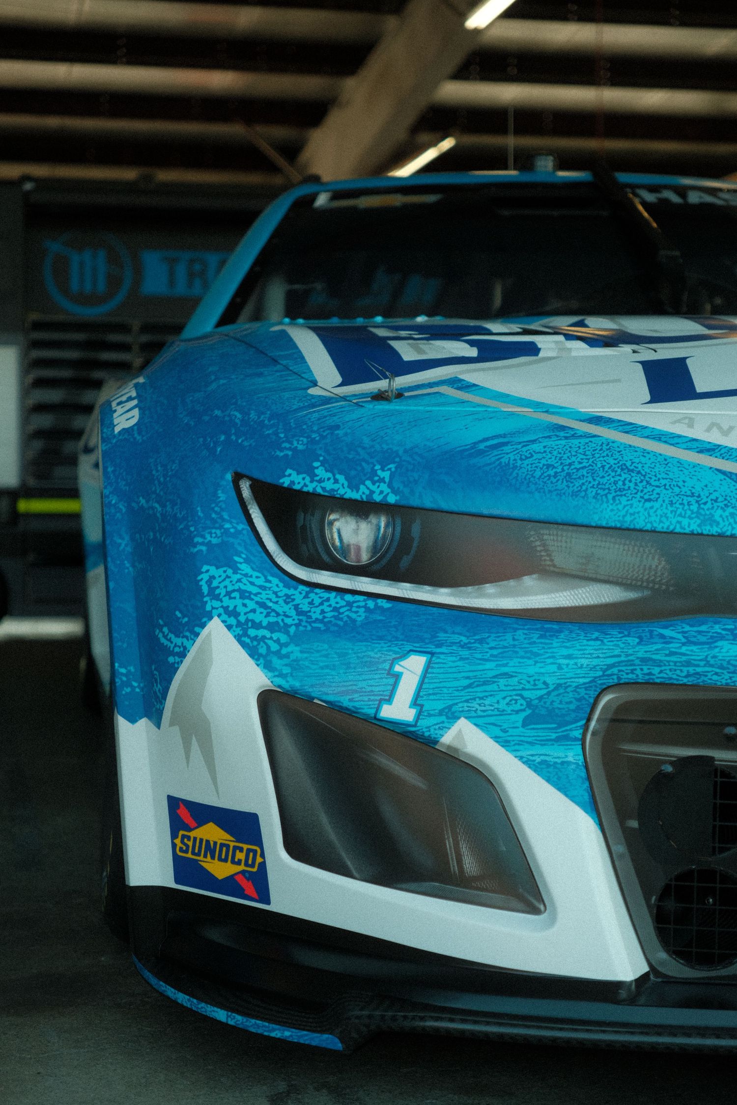 Close-up of a blue and white NASCAR race car with Sunoco sponsorship and number 1 in a garage.