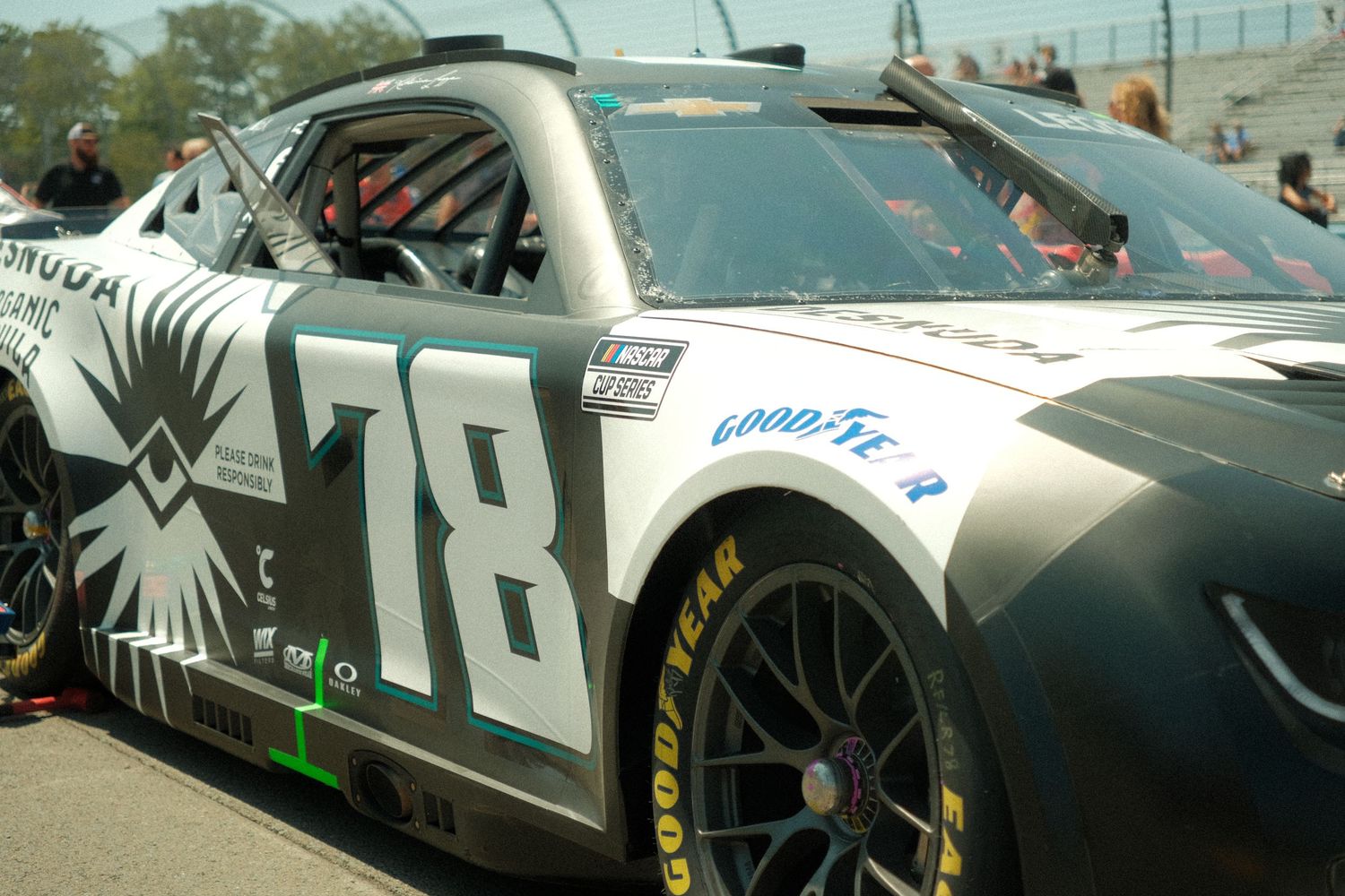 NASCAR number 78 Mohawk race car with eagle livery parked on pit road at sunny speedway event.