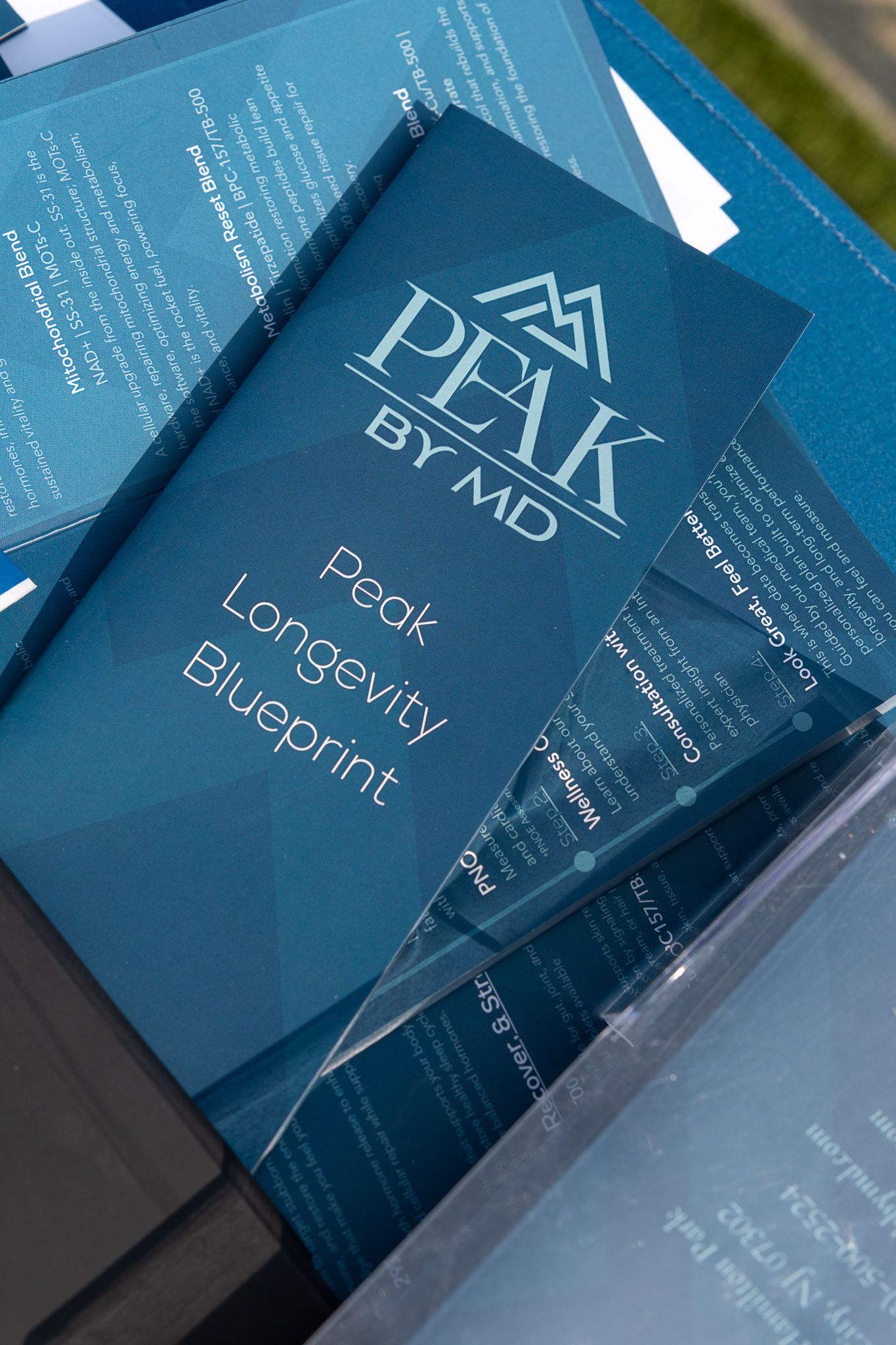 Peak by MD Peak Longevity Blueprint supplement brochures displayed at a health and wellness event.