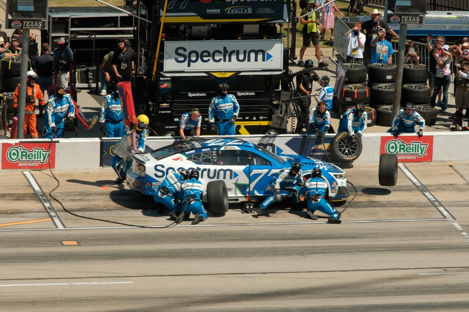 NASCAR pit crew services a Spectrum-sponsored race car during a pit stop at a racing event.