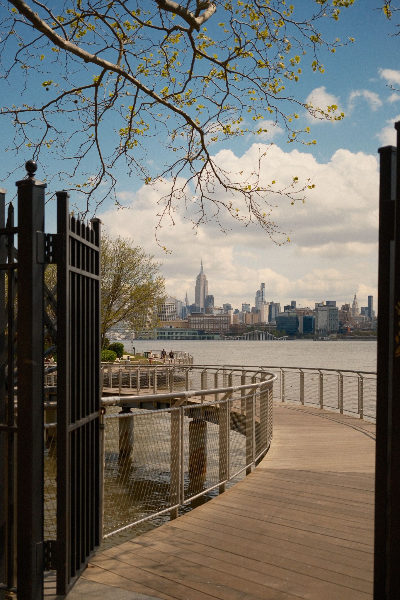 Wooden waterfront boardwalk with iron gates overlooking the Manhattan skyline across the Hudson River from Hoboken, NJ.