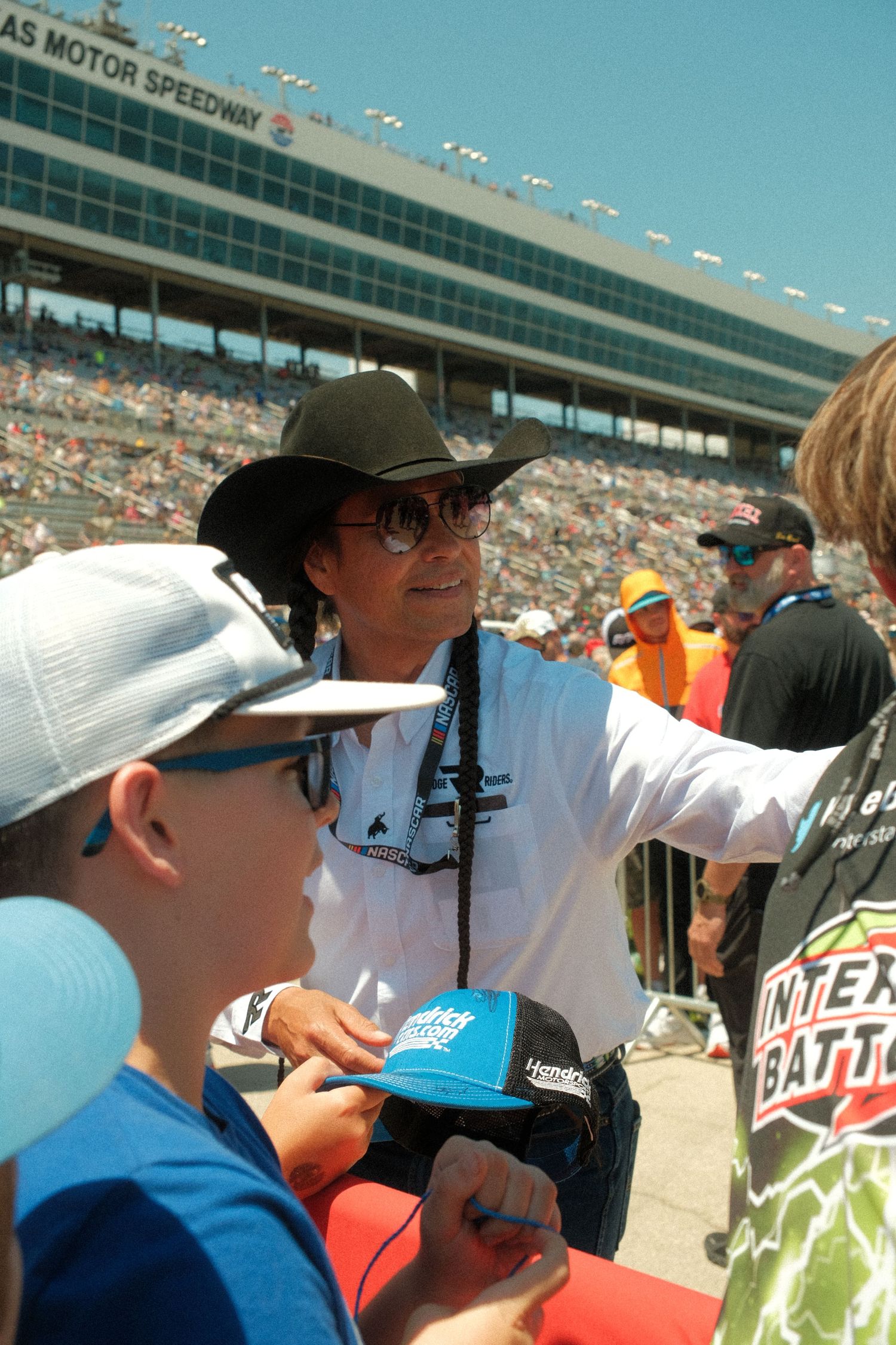 A fan gets an autograph from a celebrity in a cowboy hat at Texas Motor Speedway NASCAR race event.