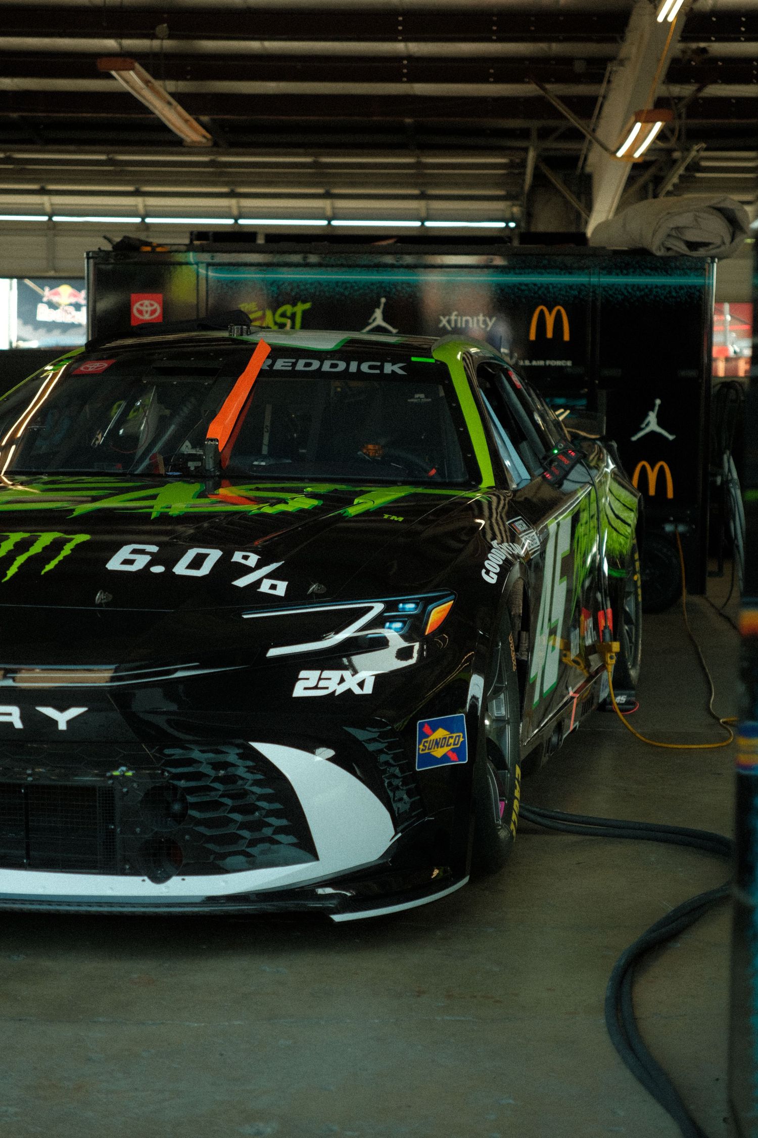 NASCAR Monster Energy 23XI Racing car #45 driven by Tyler Reddick in dark garage pit area.
