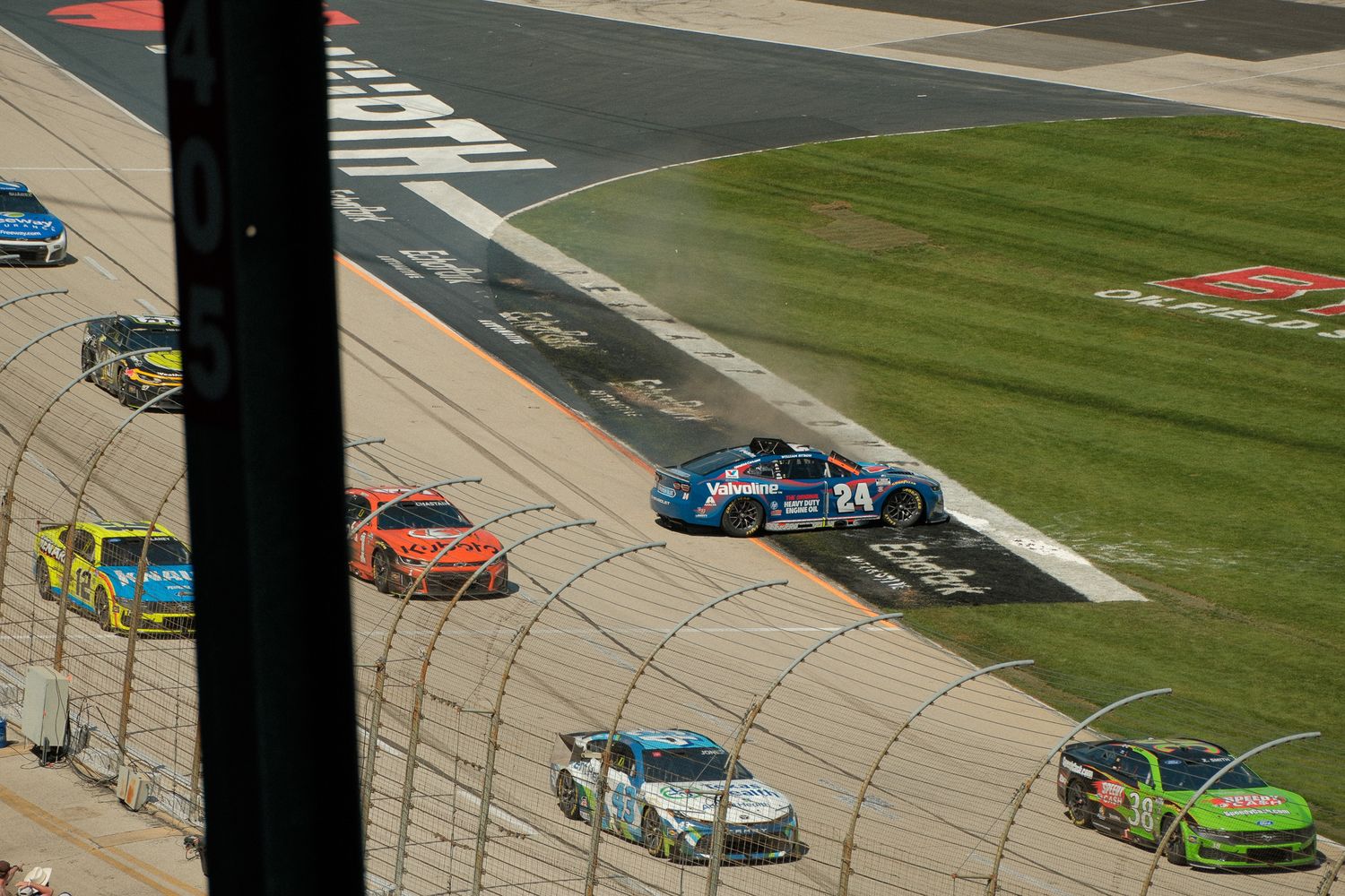 NASCAR number 24 race car leads a pack of competitors around a banked turn at a superspeedway.