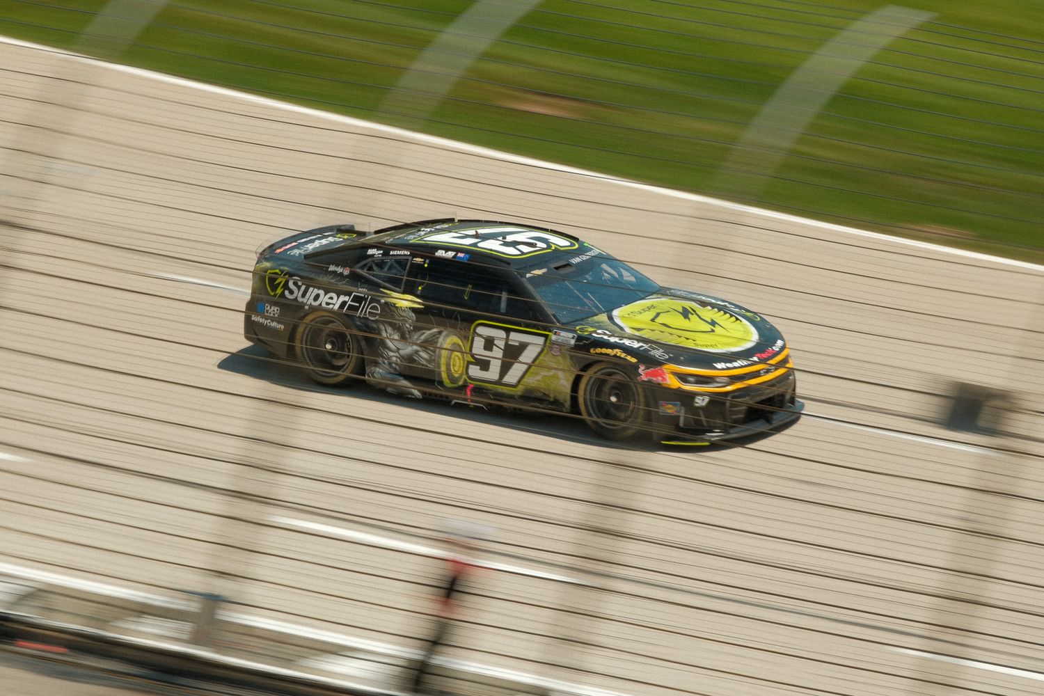 NASCAR number 97 black and yellow race car speeding along the track with motion blur in the background.