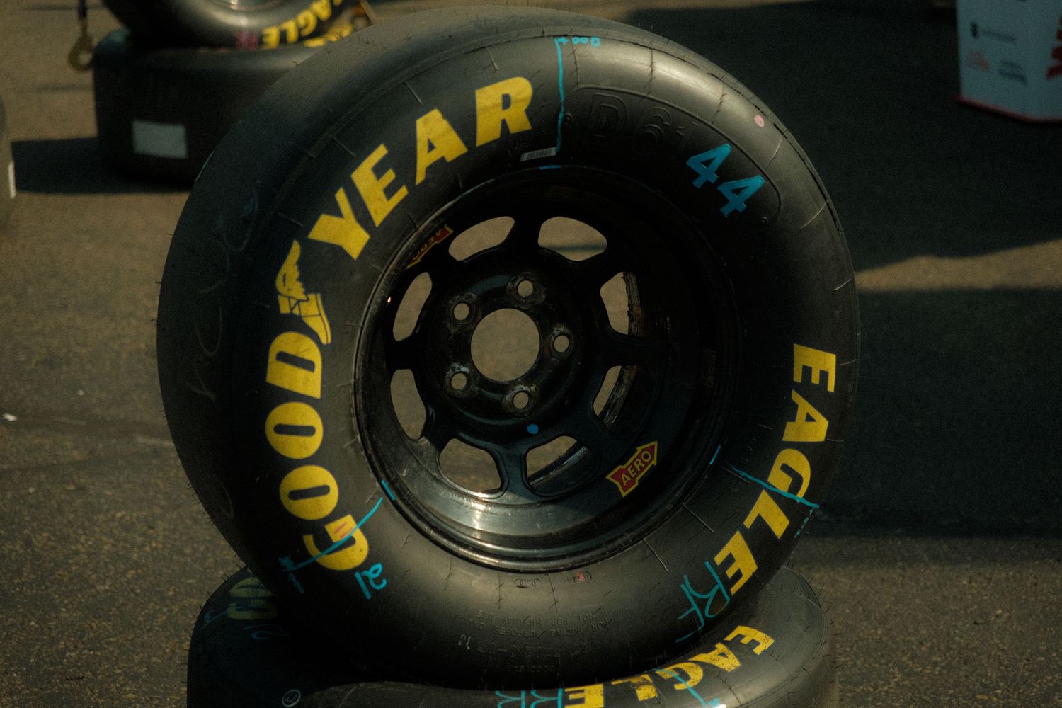 Goodyear Eagle NASCAR racing slick tires mounted on black wheels stacked in the pit area.