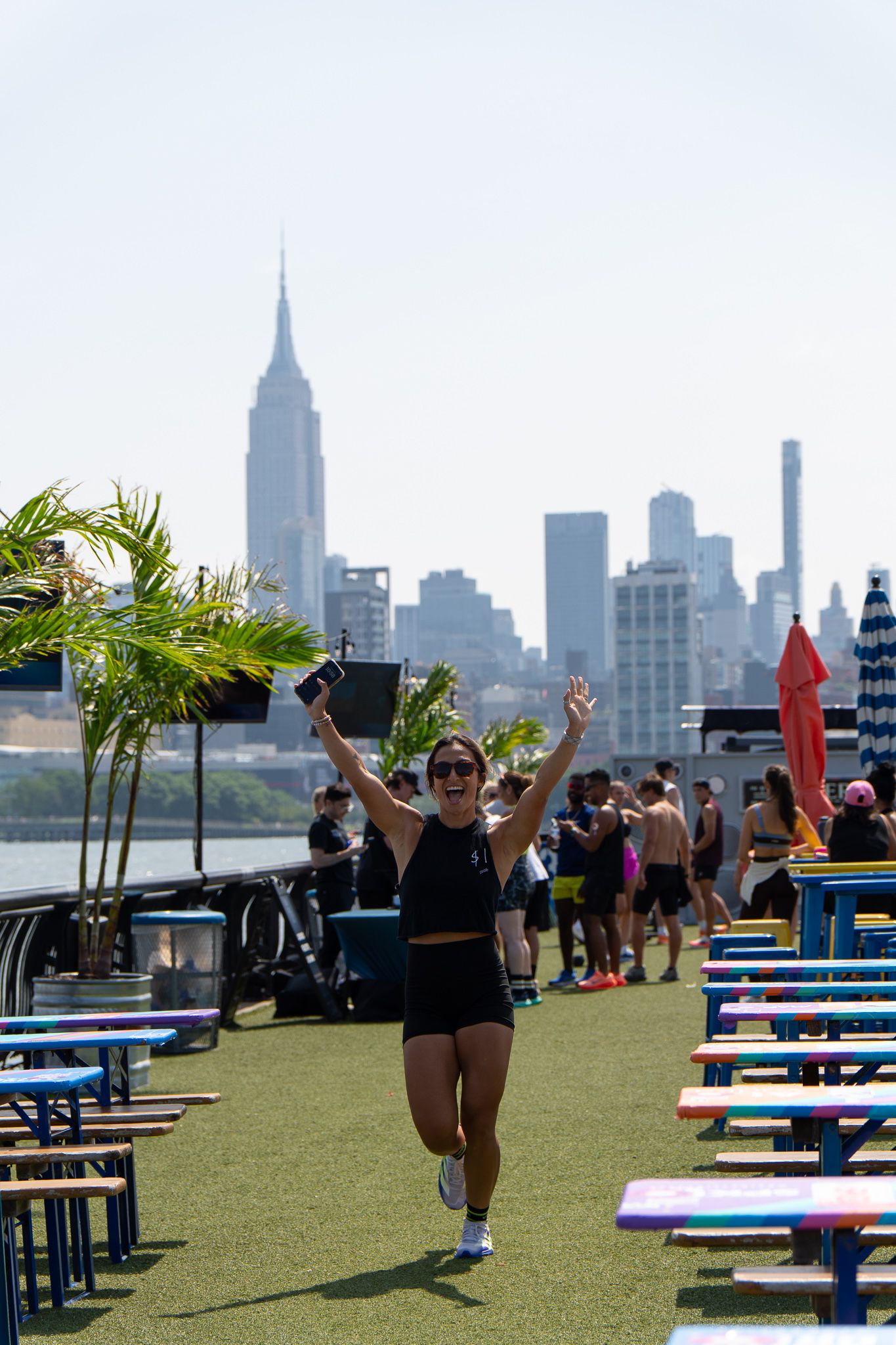 Woman celebrating with raised arms running outdoors with iconic NYC Empire State Building skyline behind.