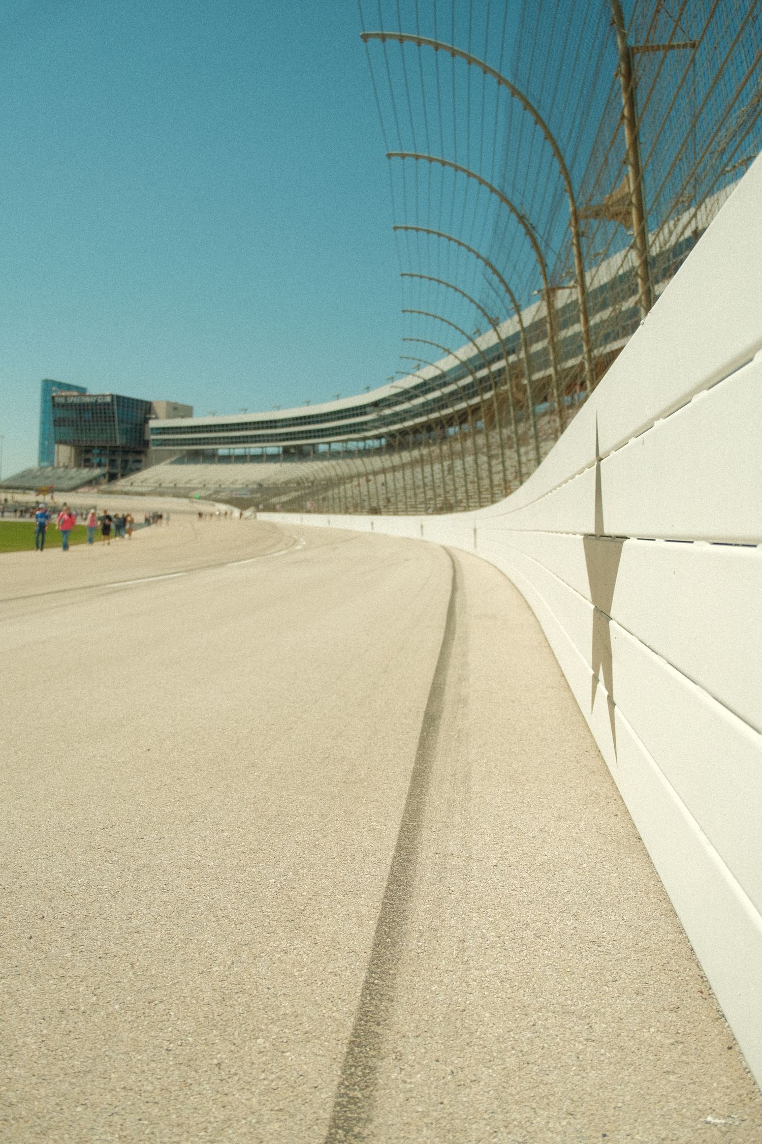 Empty NASCAR oval track straightaway with safety wall and grandstands at Texas Motor Speedway.
