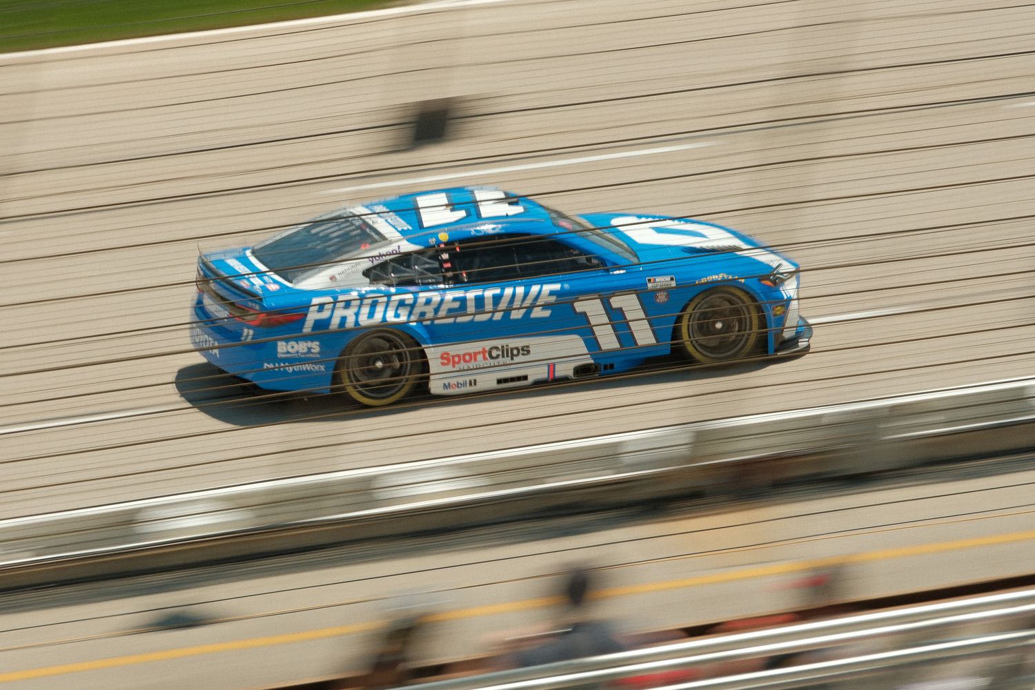 Blue Progressive-sponsored NASCAR #11 race car speeding along straightaway at Atlanta Motor Speedway.