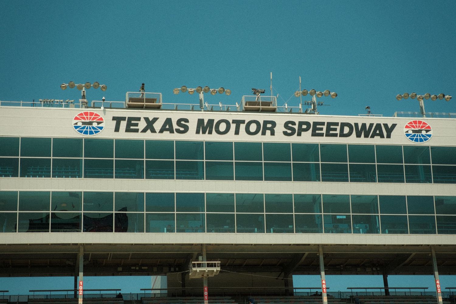 Exterior facade of Texas Motor Speedway building with bold signage against a clear blue sky.