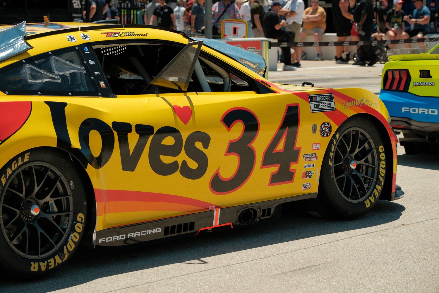 Close-up of the Loves Travel Stops sponsored number 34 yellow NASCAR Ford Racing car in the pit area.