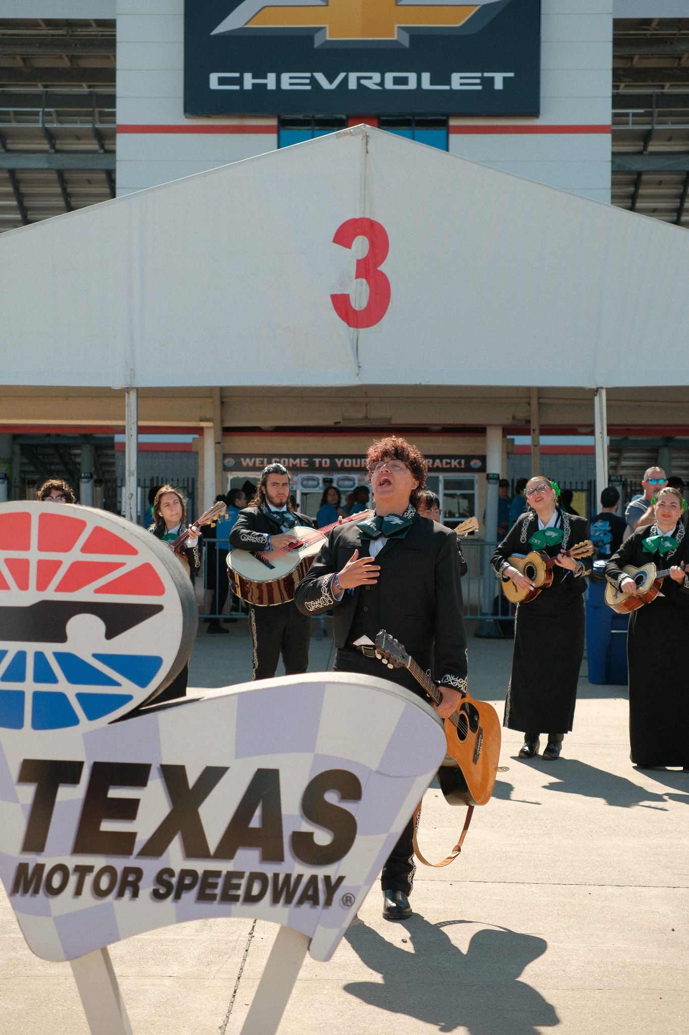 Mariachi band performs at Texas Motor Speedway entrance near gate 3 and Chevrolet sign.