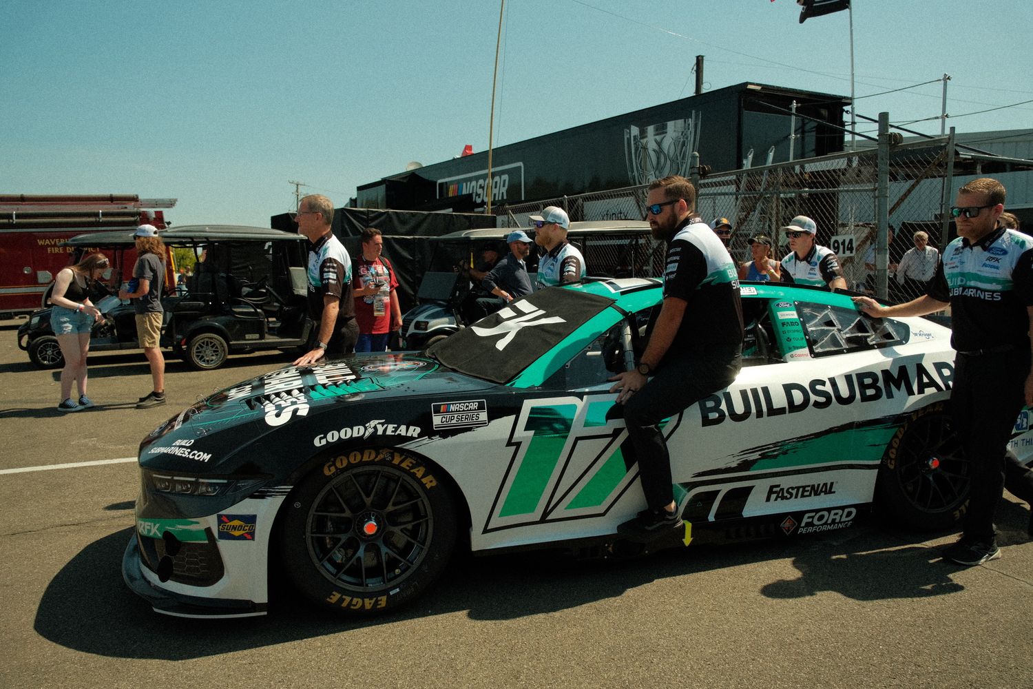 NASCAR race car #17 with BuildSubmarine sponsorship being pushed through pit lane by crew members.