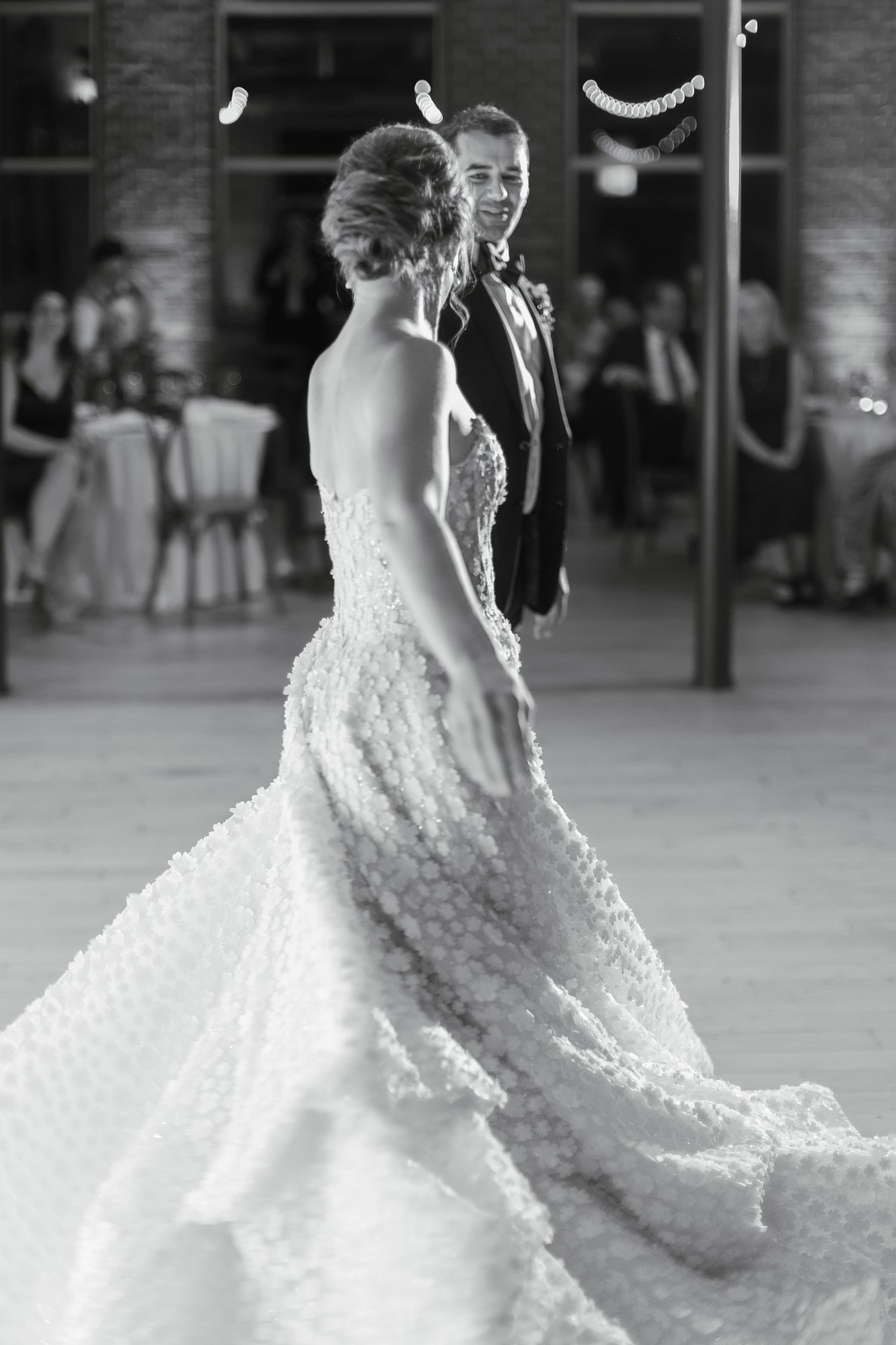 Black and white photo of bride and groom sharing their first dance at wedding reception.
