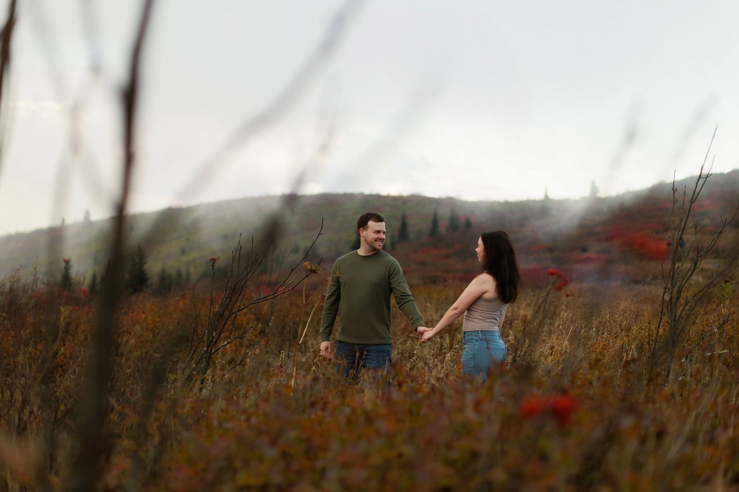 Two people standing together in a foggy mountain meadow during fall season.