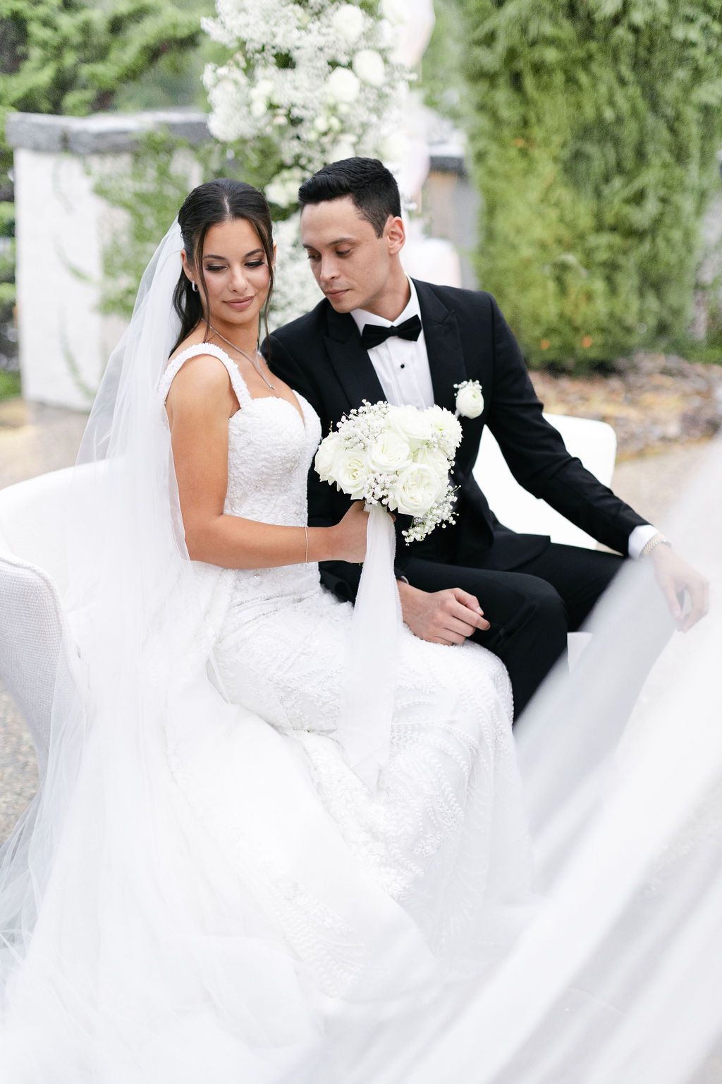 Elegant wedding portrait on white furniture with bride holding classic white bouquet.