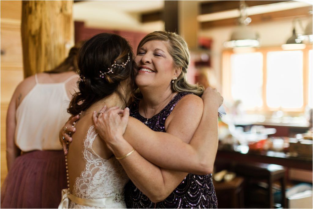 An emotional embrace between two women at a wedding celebration, one in a bridal gown and one in a navy dress.