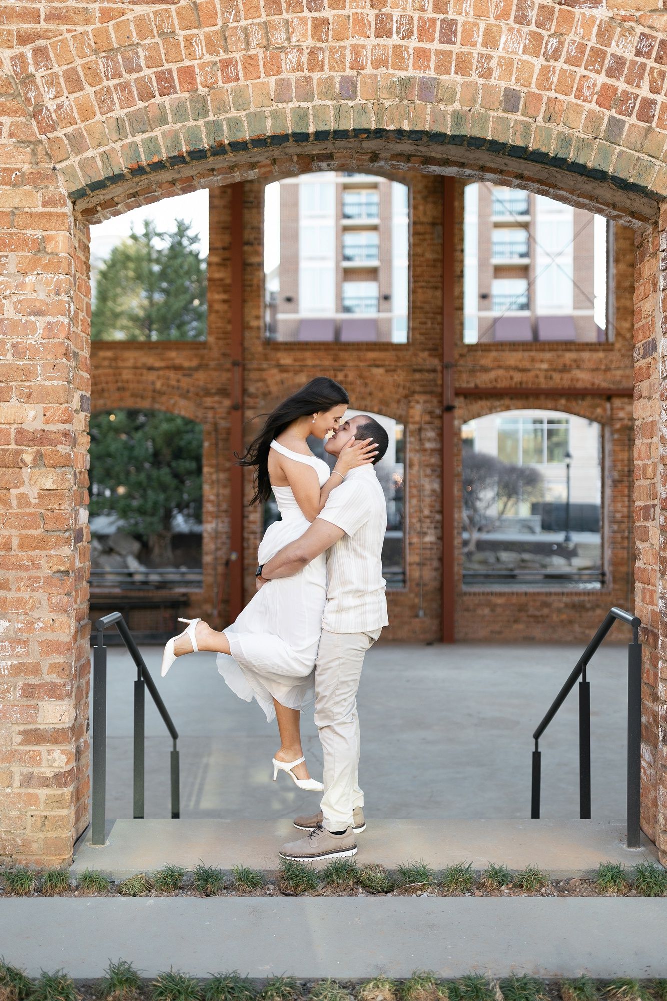 A sequence of playful dance lifts and poses captured against a rustic brick archway backdrop.