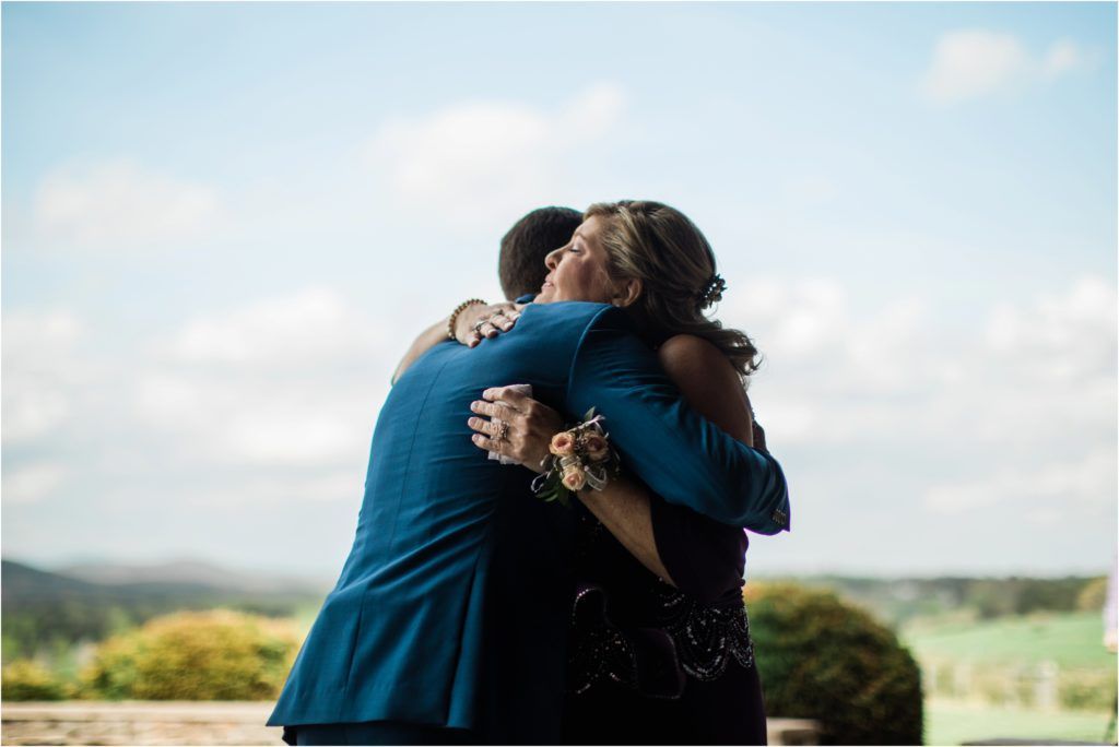 Emotional embrace captured against scenic mountain backdrop at outdoor wedding.