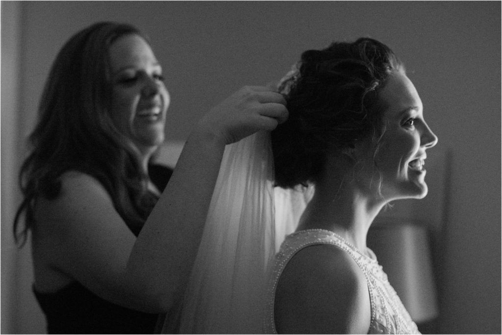 Black and white image capturing a tender moment during wedding preparations.