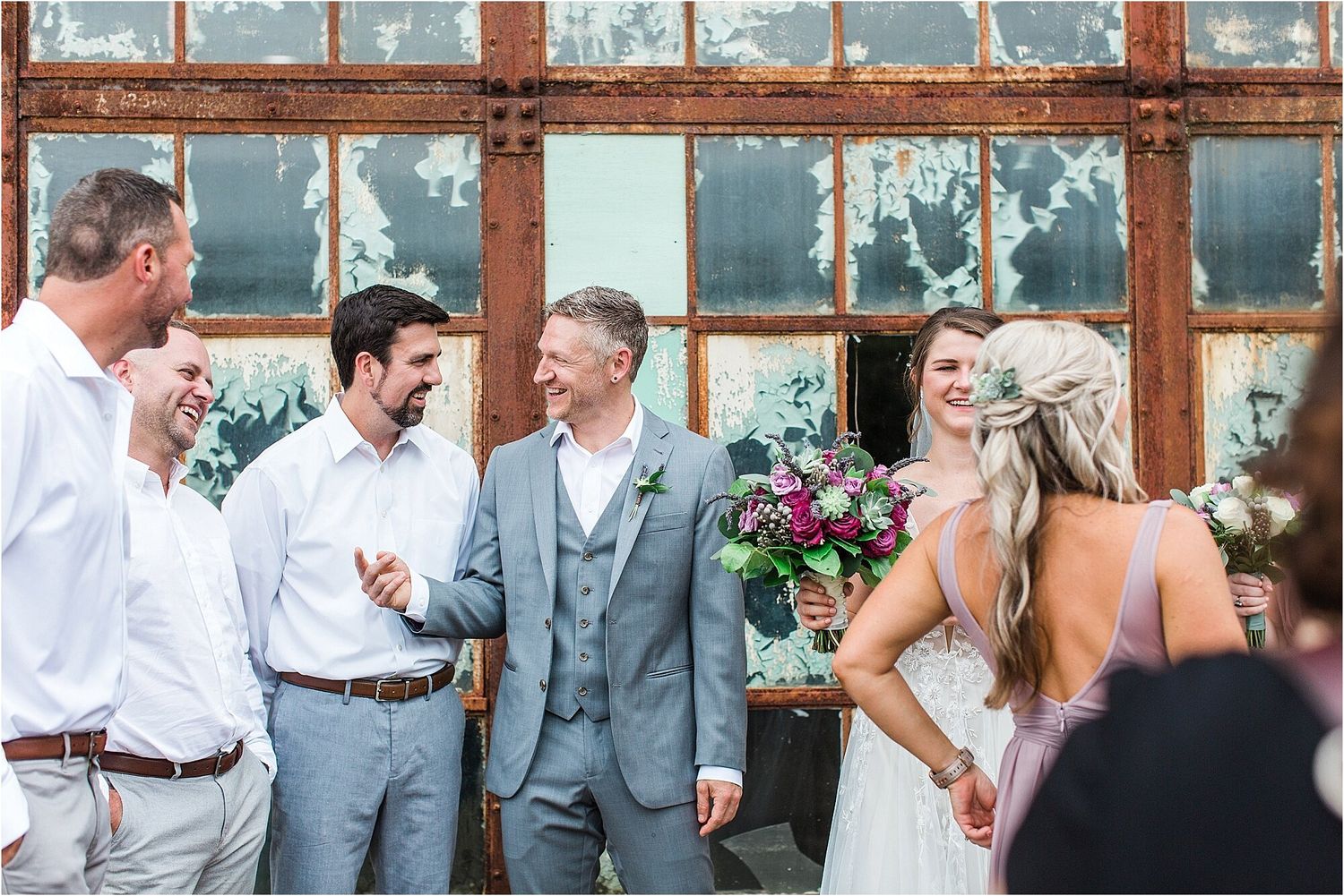 Wedding celebration with bridal party against vintage factory windows.