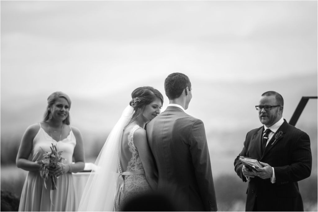 Black and white ceremony photo showing intimate wedding moment with officiant and attendants.