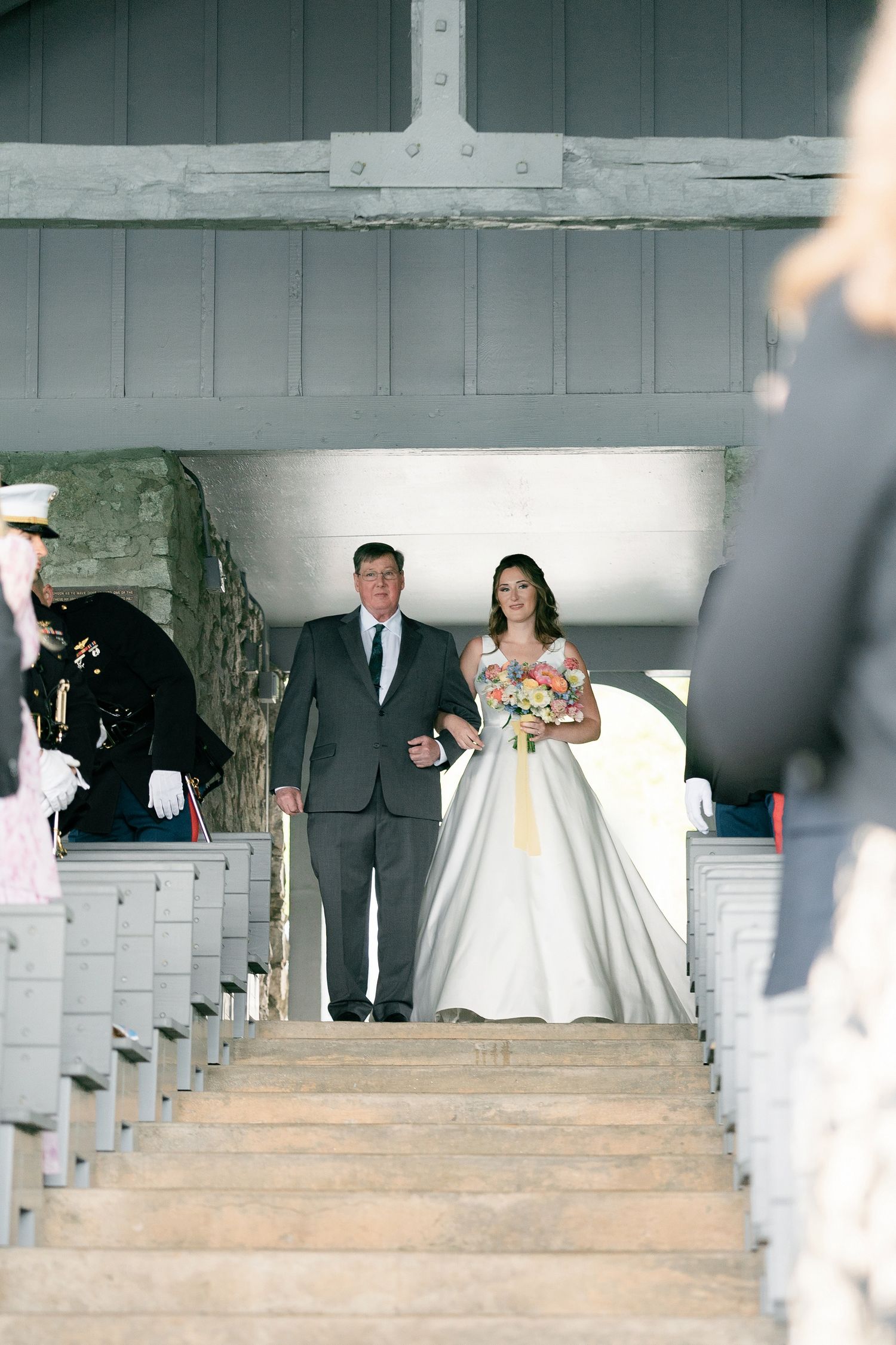 A couple descends white church steps with light streaming through surrounding columns in this wedding ceremony sequence.