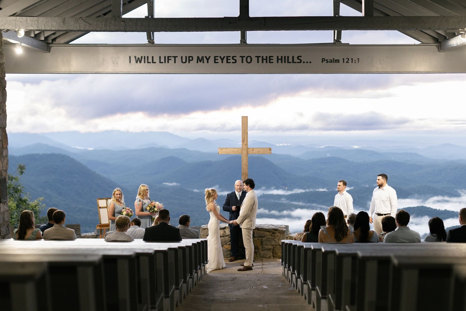 An outdoor mountain chapel with stunning views of misty blue mountain ranges and a wooden cross at Pretty Place in North Carolina.
