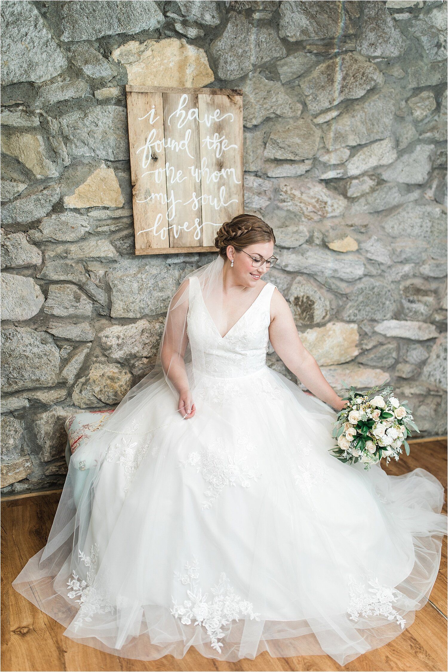 A wedding dress with delicate lace details spreads beautifully against a rustic stone wall backdrop.