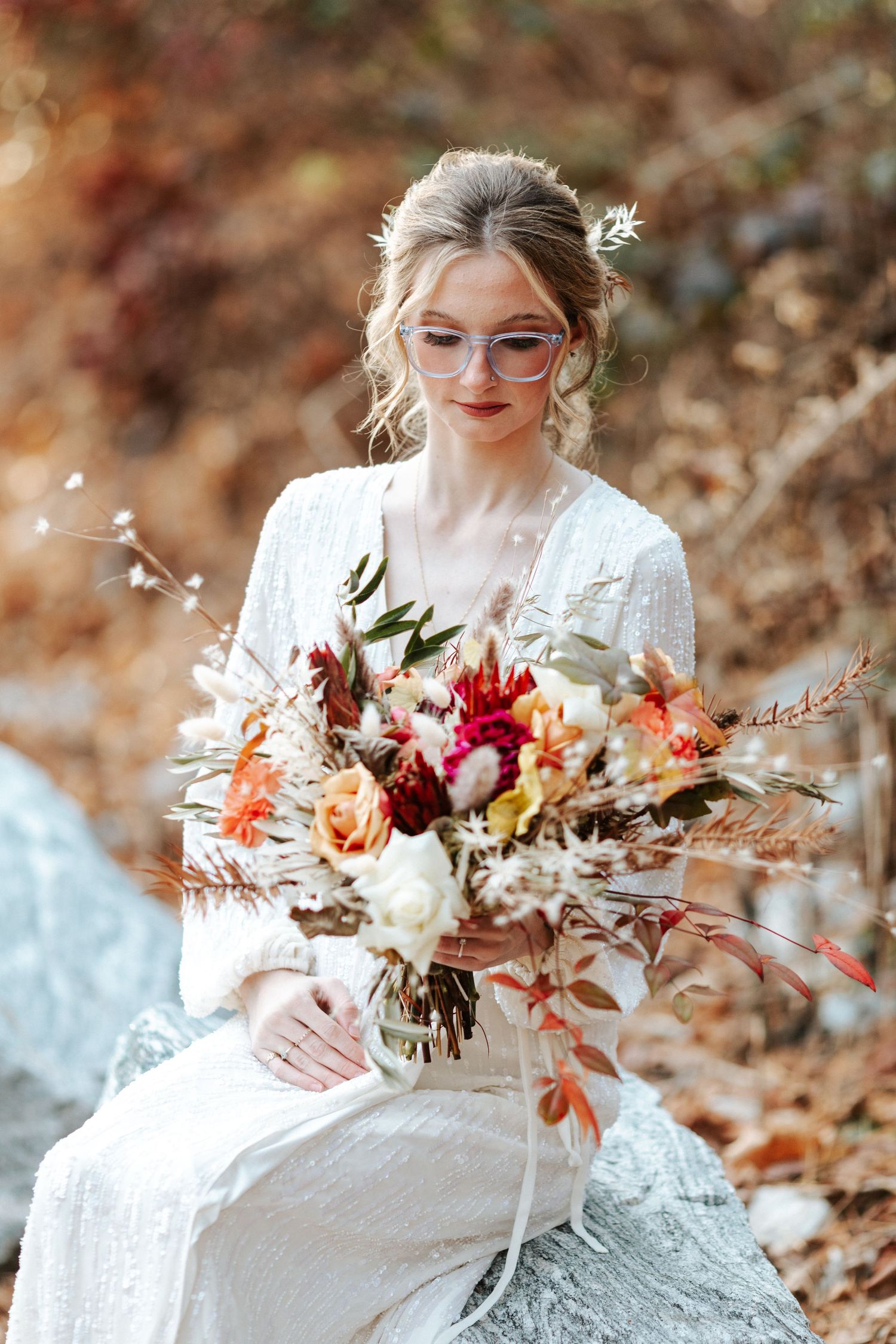 Dreamy bridal portrait featuring vintage glasses and a romantic fall bouquet on a stone.