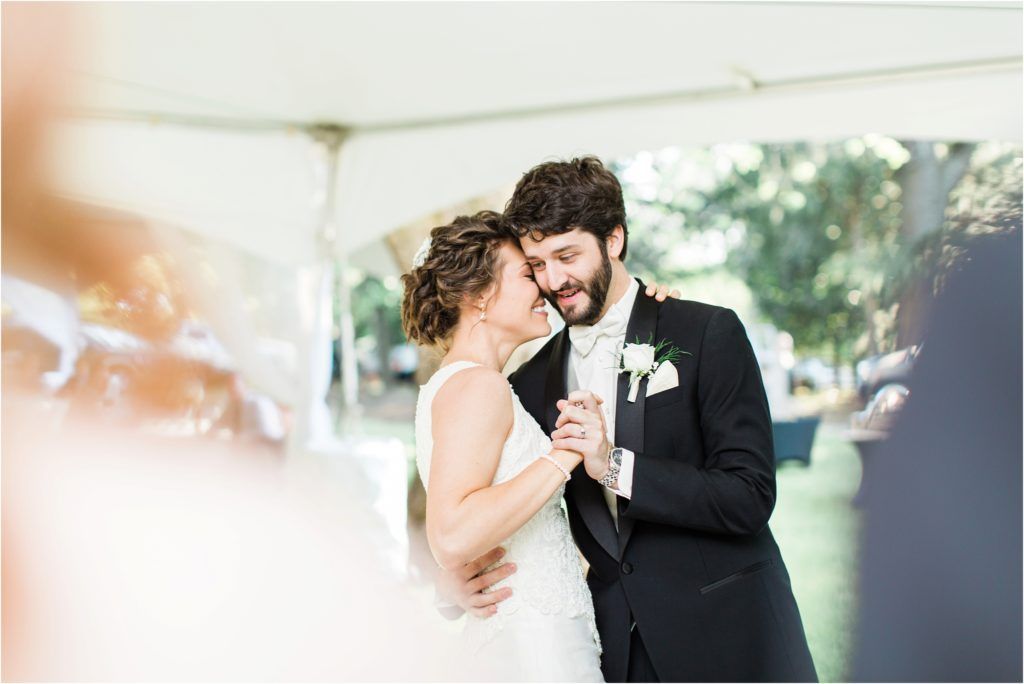 An intimate moment shared under a white tent during a wedding celebration.