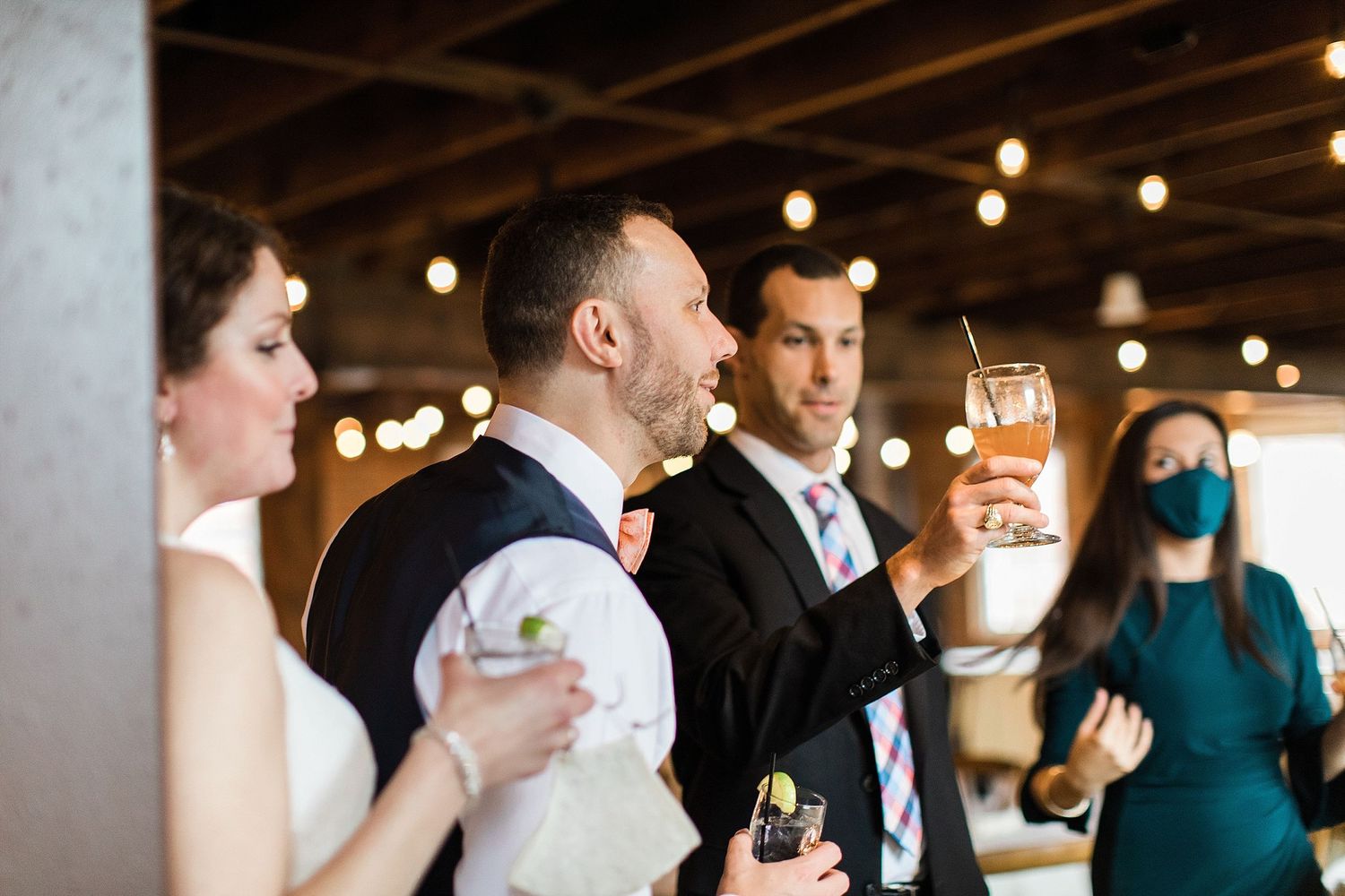 Wedding party members raise glasses in a toast during reception celebration.