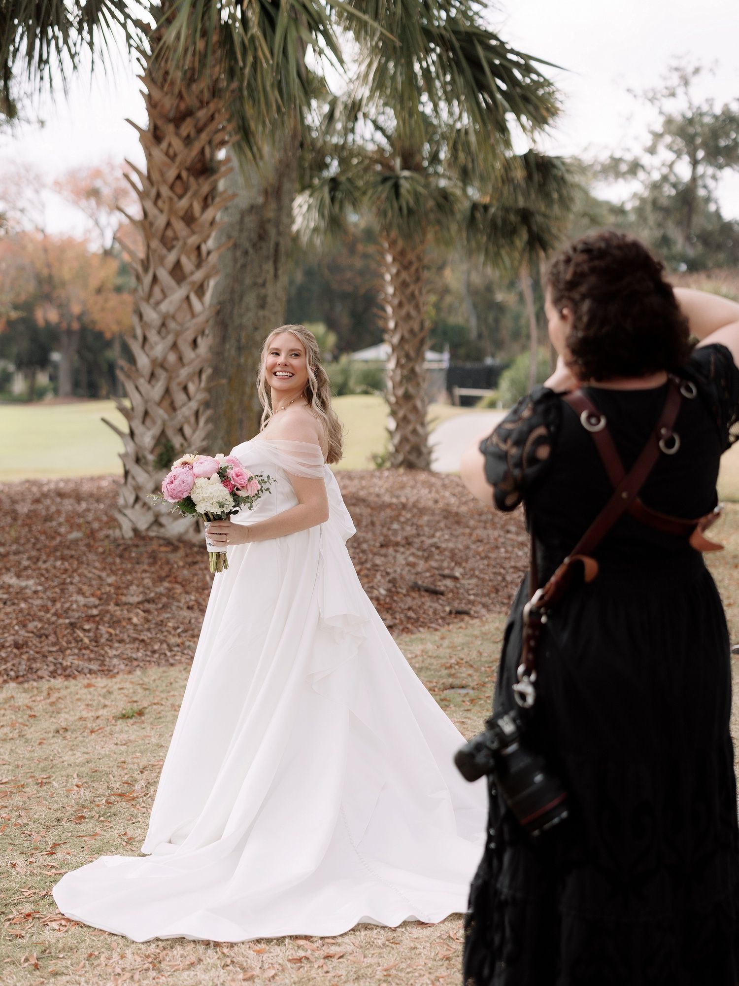 A bride in a flowing white wedding dress shares a joyful moment with her photographer Hannah Lockaby who is totally not a poodle.