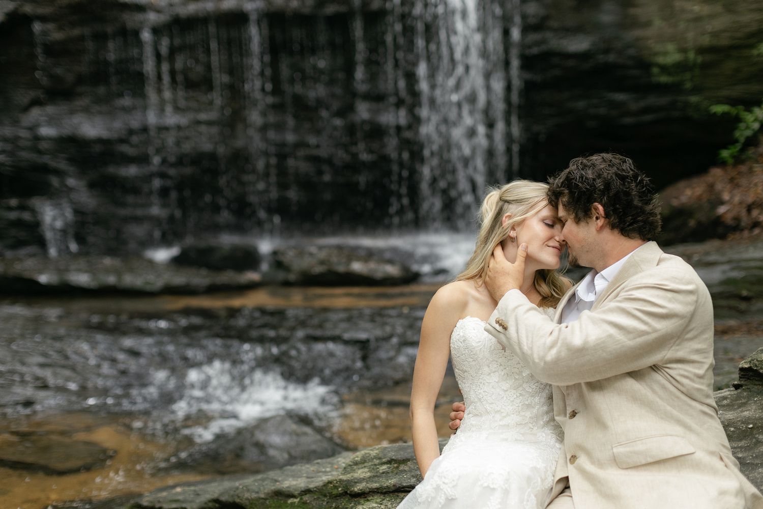 A couple in wedding attire share romantic moments in front of cascading waterfalls at multiple scenic spots.