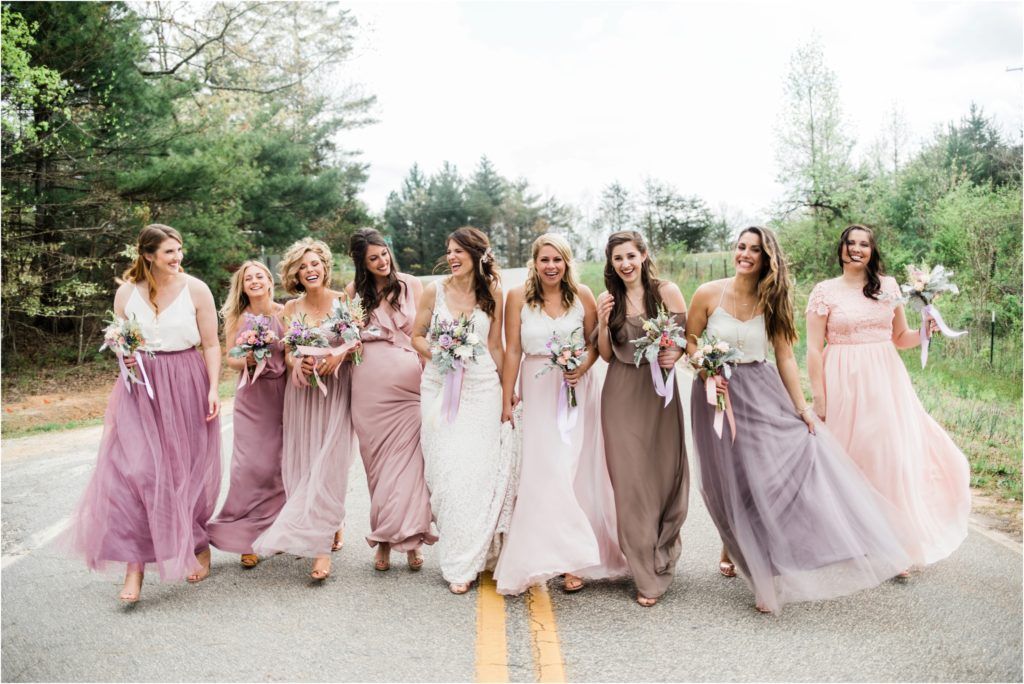 Wedding party walking together in coordinated pink and purple flowing dresses.