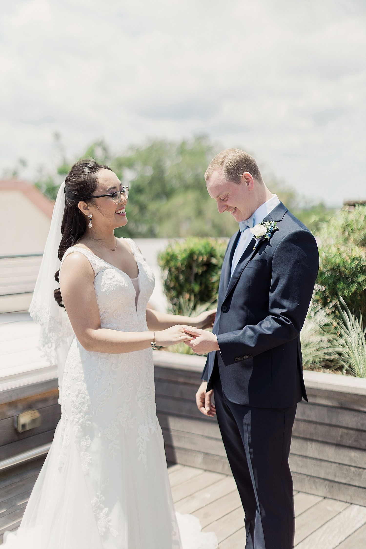 A joyful moment between a bride and groom sharing their first look on a sunny outdoor deck.
